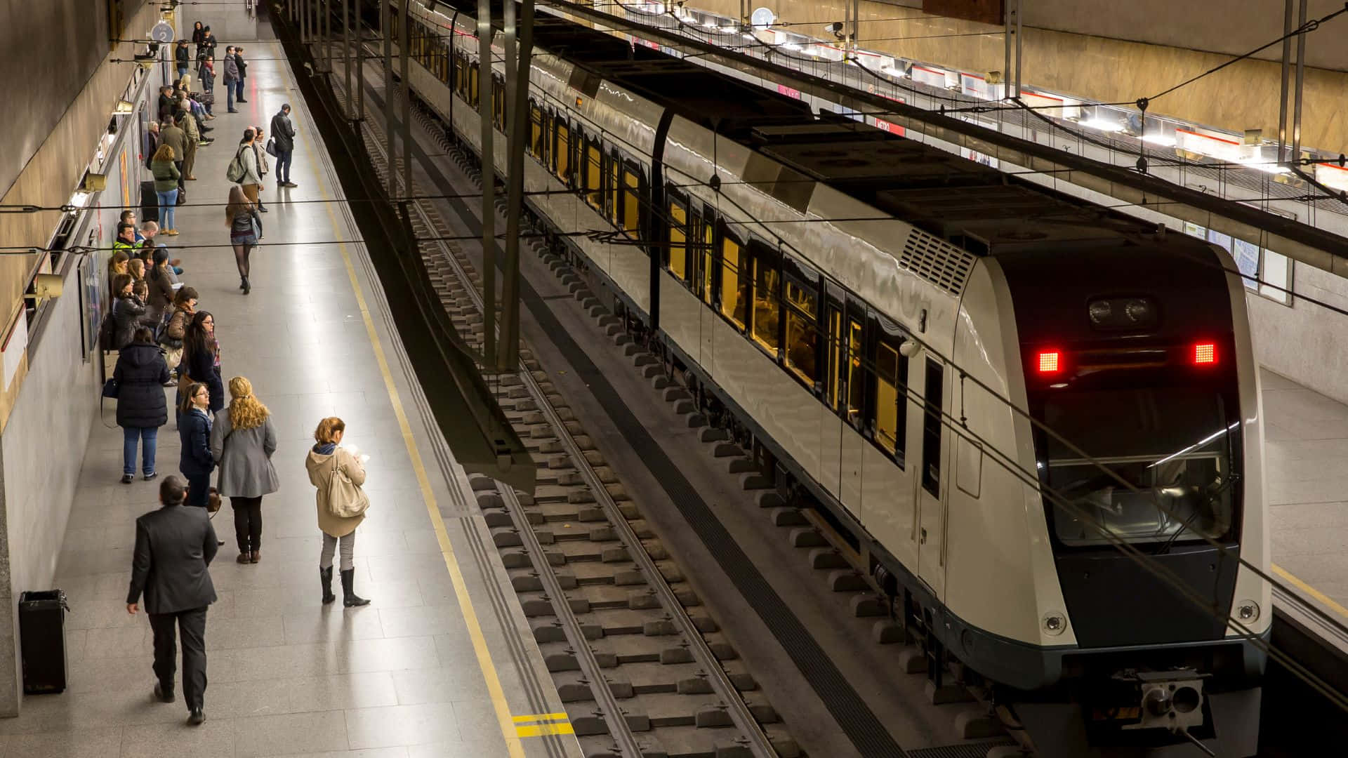 Subway 桌布 壁紙 — 一列現代地鐵列車到達繁忙的地下車站，乘客在月台上等候。