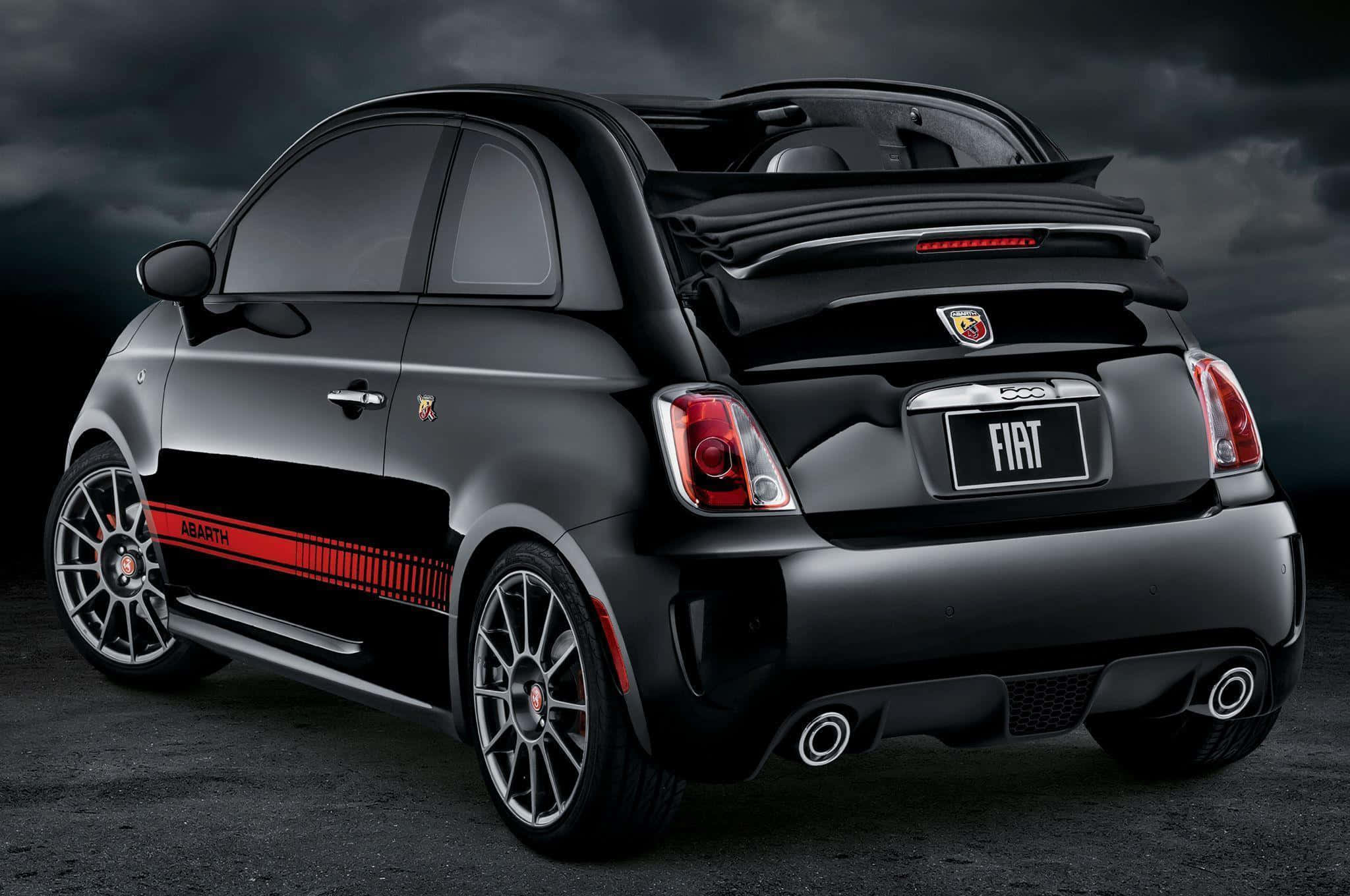 Abarth 桌布 壁紙 — 一台時尚的黑色Fiat 500 Abarth，帶有紅色點綴和雙排氣管，在暴風雨的天空下蓄勢待發。
