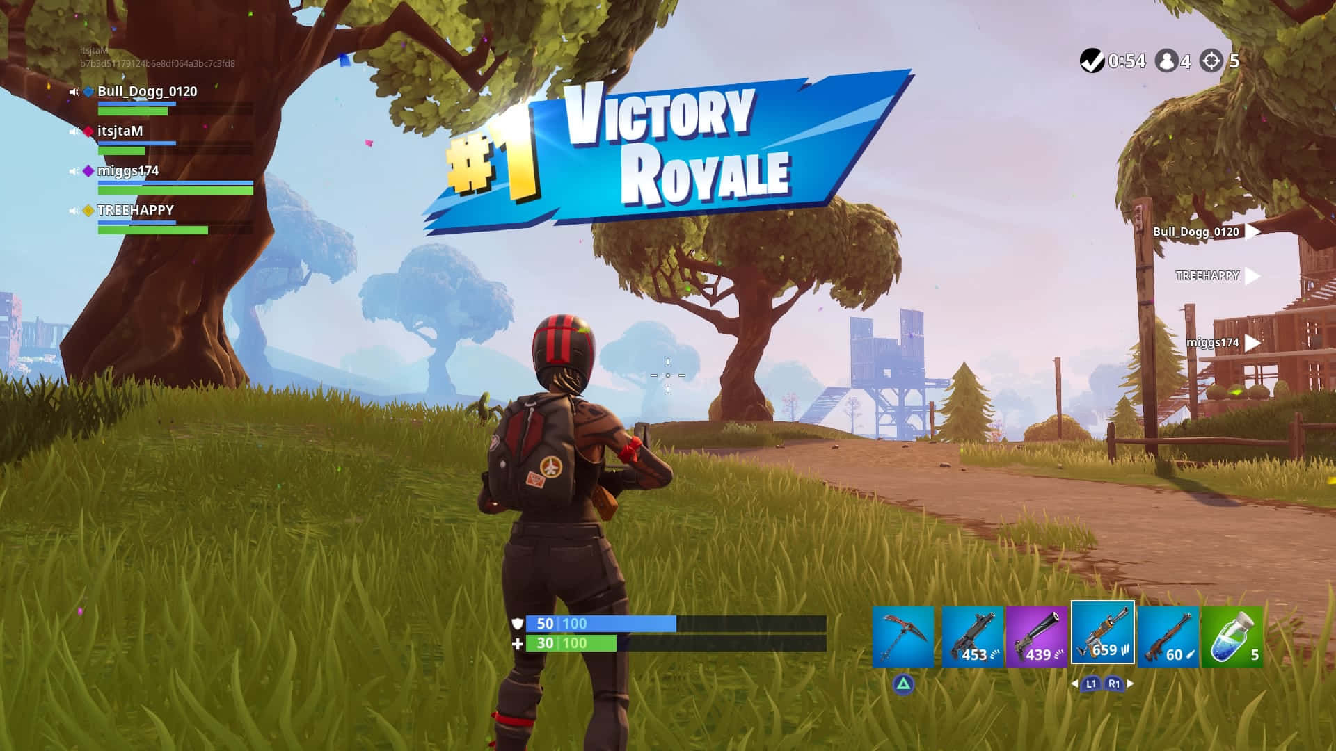 Fortnite Battle Royale 桌布 壁紙 — 一名《Fortnite》玩家站在草地上，背景有藍色勝利皇冠旗幟、樹木和遠處建築物。