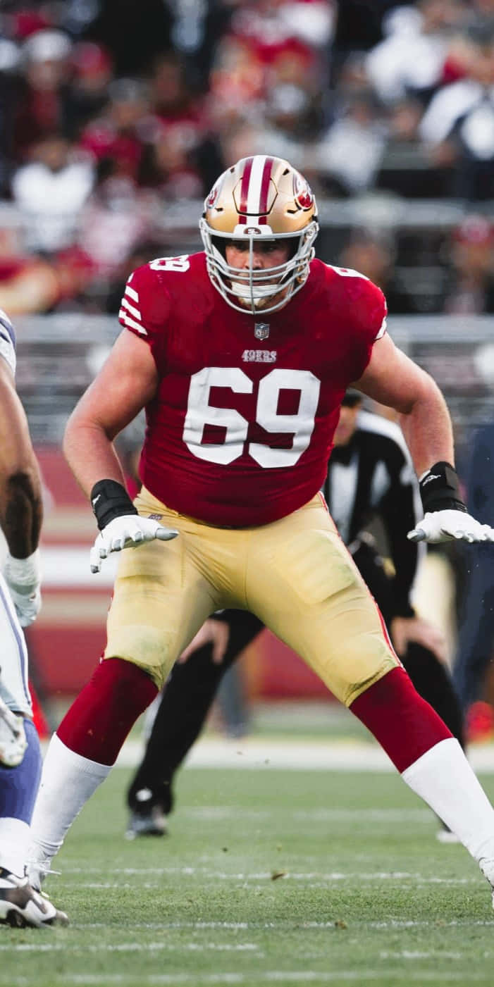 Mike Mcglinchey 桌布 壁紙 — 一名三藩市四九人隊的足球員，身穿紅金色69號球衣，在比賽期間準備就緒，站在綠色球場上。