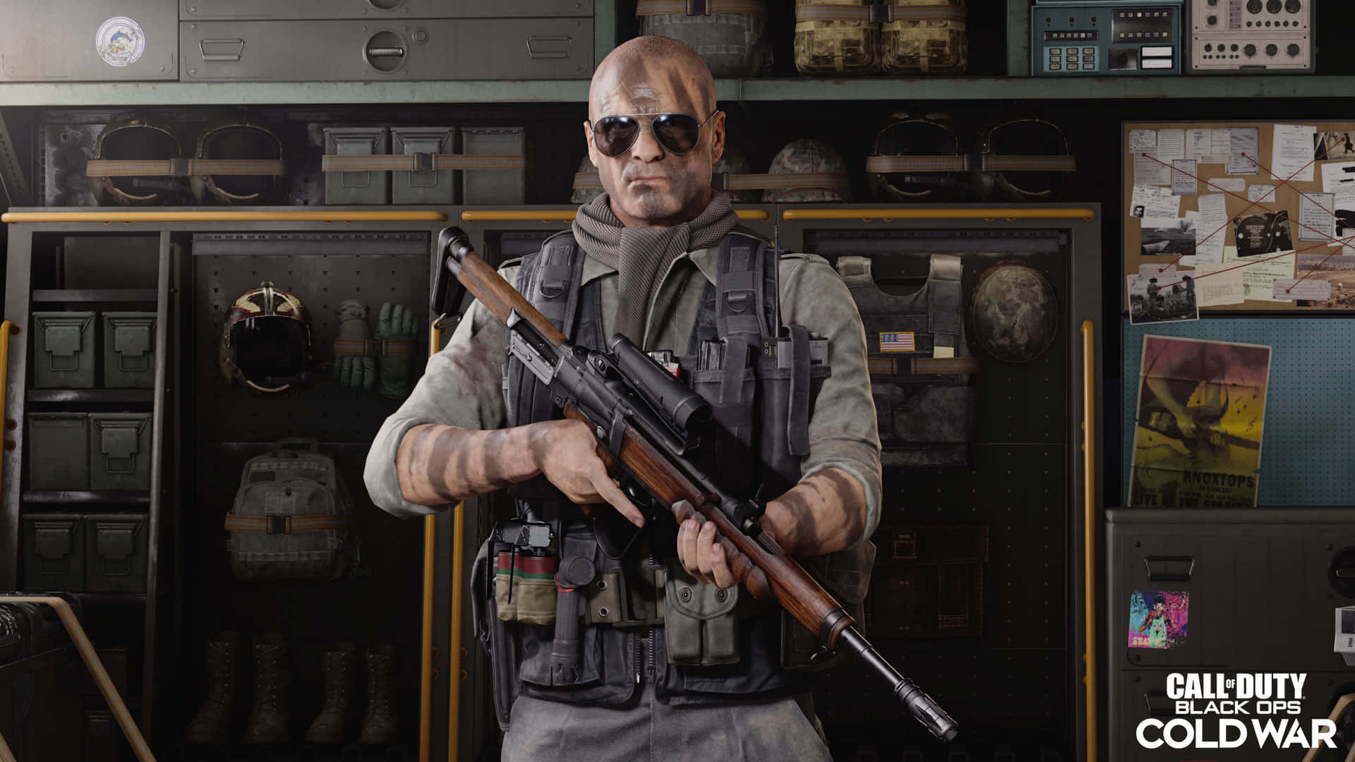 Call Of Duty Black Ops Cold War 桌布 壁紙 — 一名光頭士兵戴著太陽眼鏡，在雜亂的軍事裝備室裡拿著狙擊步槍。