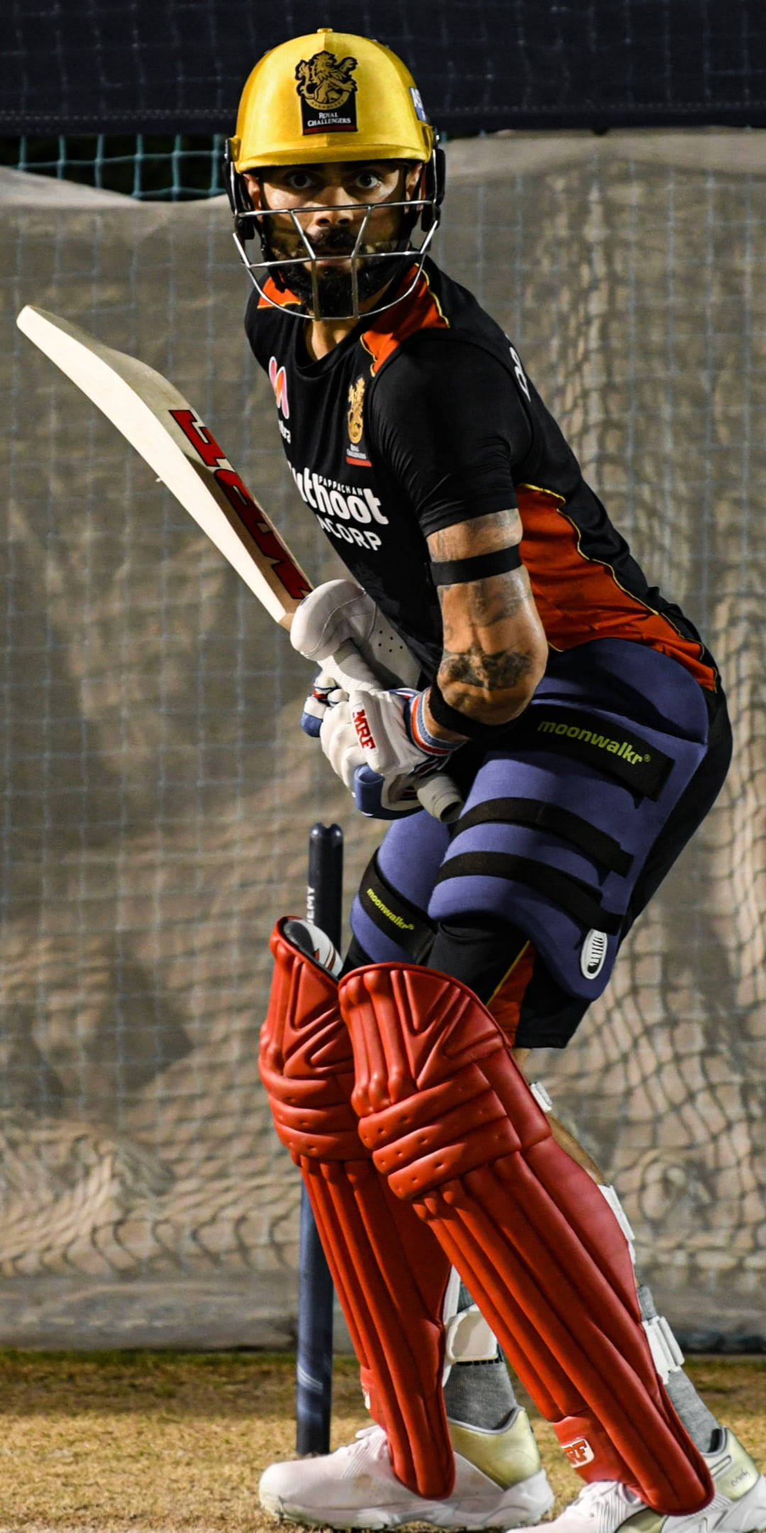 virat kohli rcb 桌布 壁紙 — 一名全副裝備的板球擊球手在體育場燈光下準備好球棒，隨時準備行動。