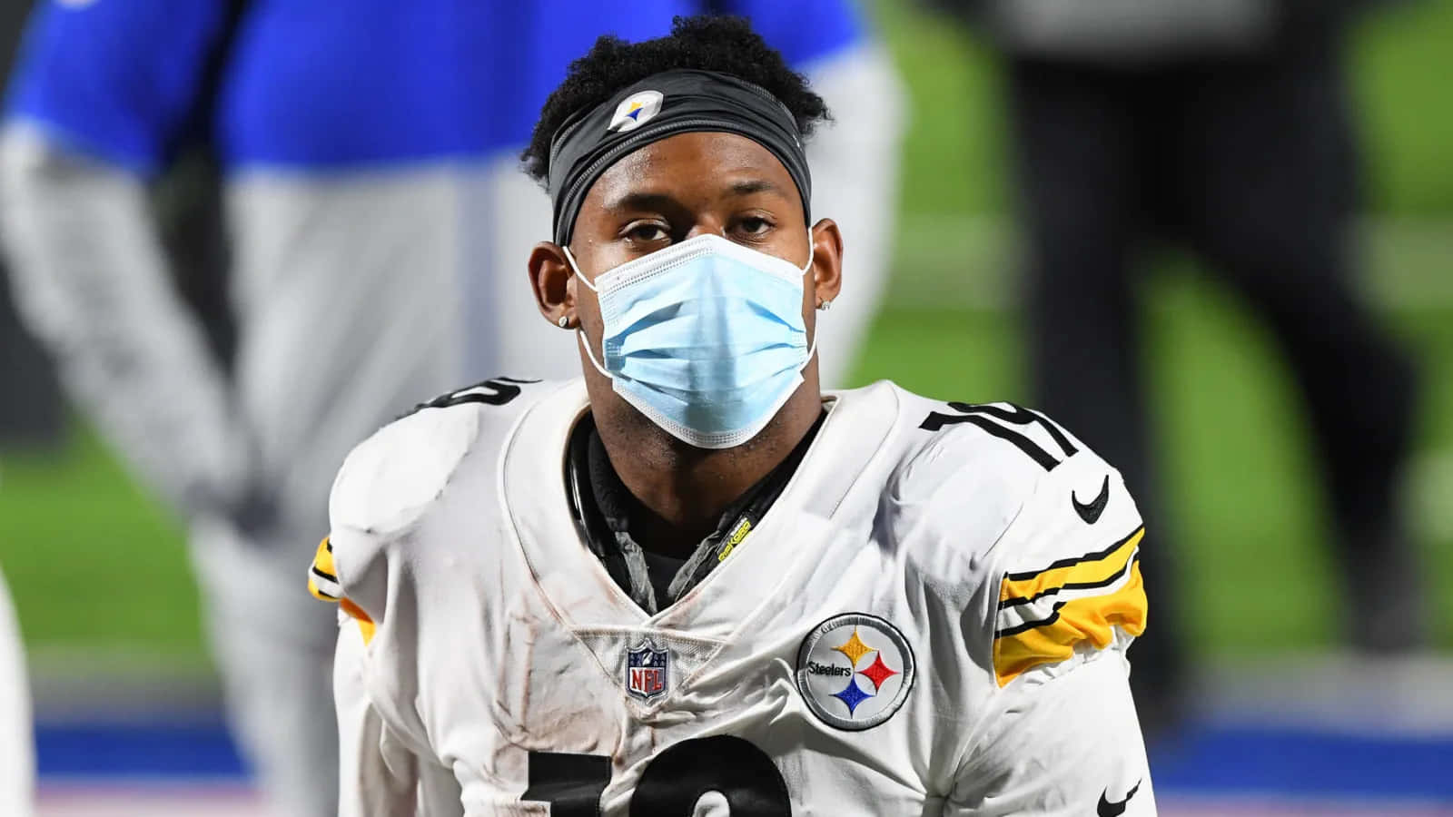 Juju Smith Schuster 桌布 壁紙 — 一名匹茲堡鋼人隊美式足球員戴著面罩和制服，在球場燈光下專注地看著球場。