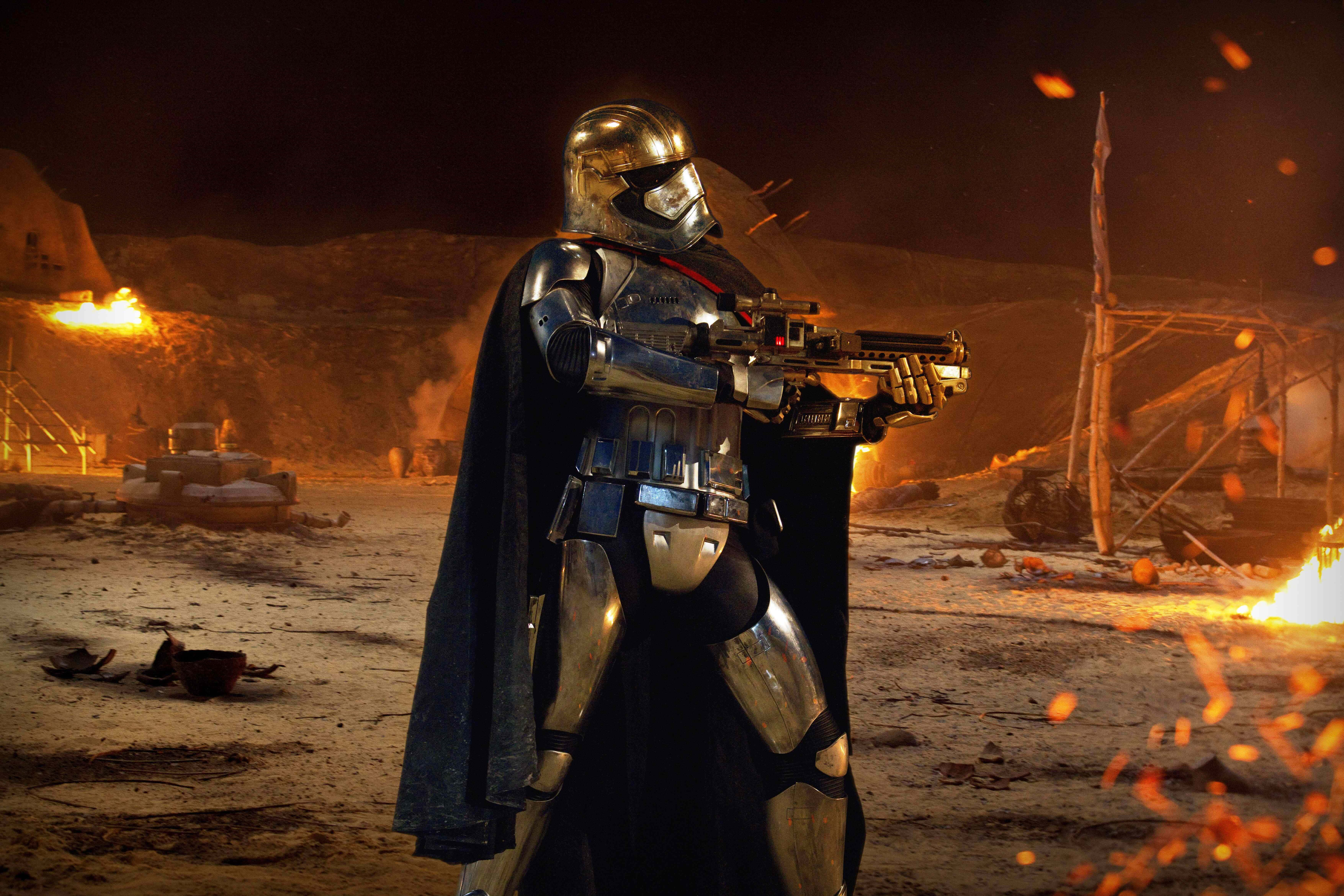 Captain Phasma 桌布 壁紙 — 一名在戰鬥中受損、身穿銀色盔甲的複製人士兵，在夜晚燃燒的沙漠戰場上手持爆能槍準備就緒。