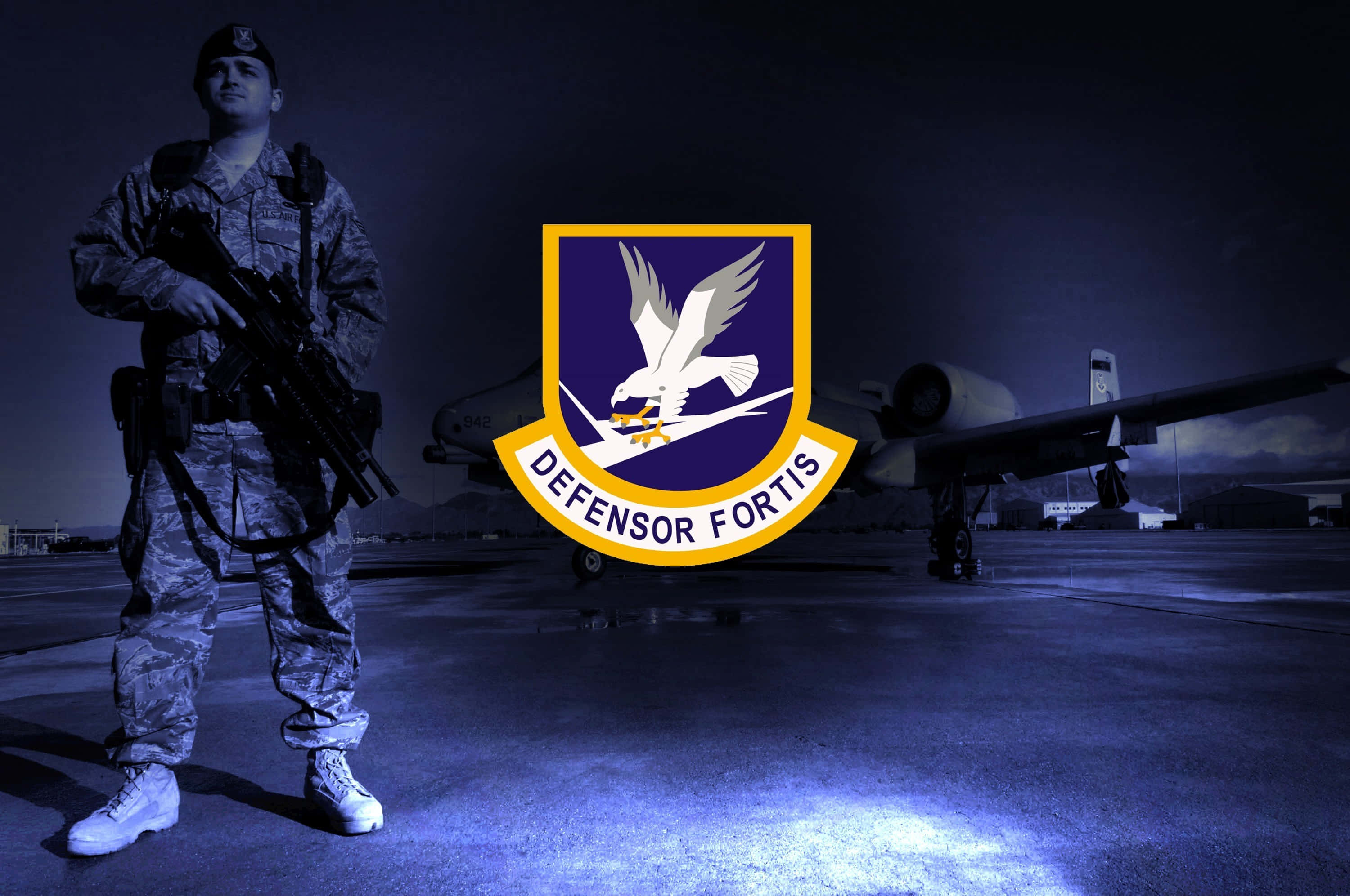 Air Force 桌布 壁紙 — 一名士兵在深藍色夜空下的軍用飛機旁立正，前景有一個發光的標誌。