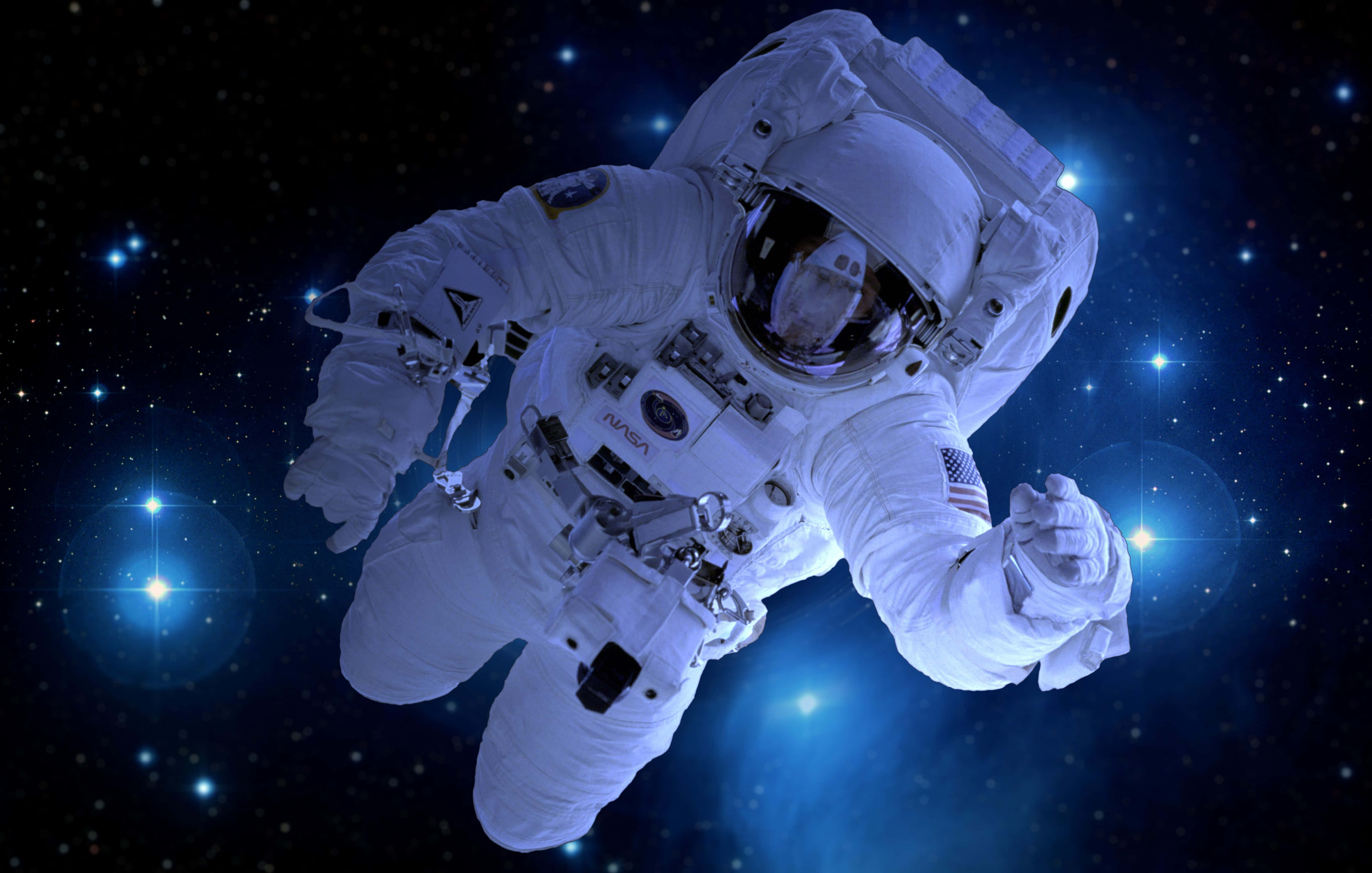Deep Space 桌布 壁紙 — 一名太空人在深邃太空中失重漂浮，周圍是發光的藍色星星和宇宙光。