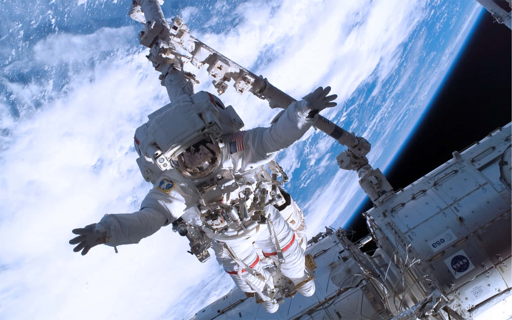 Iss 桌布 壁紙 — 一名太空人漂浮在國際太空站外，地球的藍白雲層在下方彎曲。