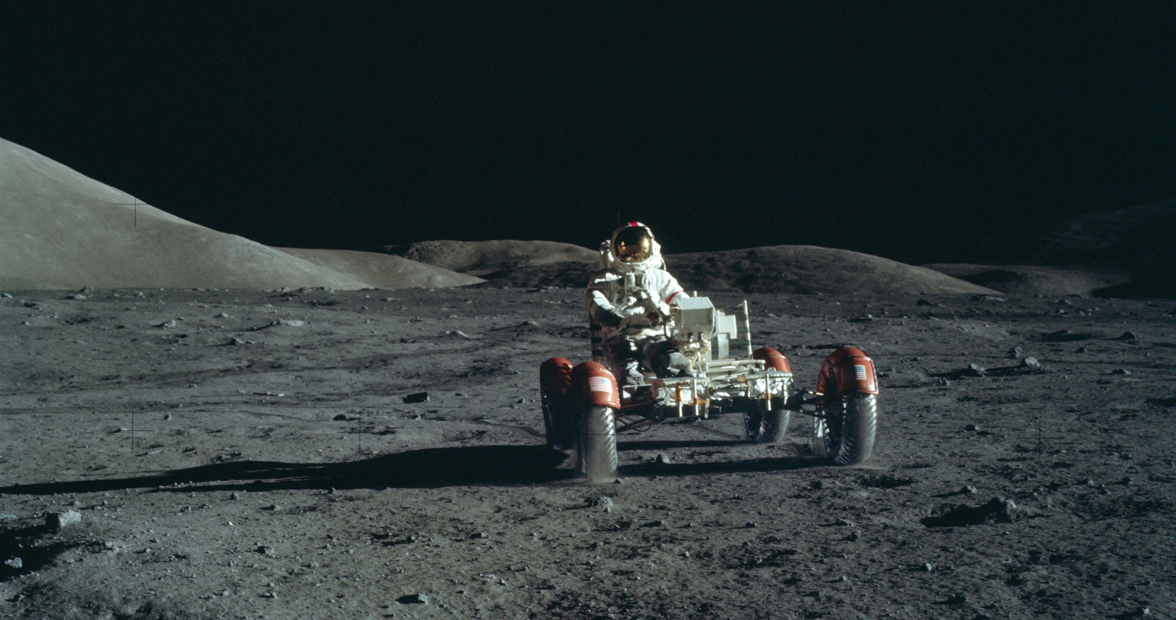 nasa 桌布 壁紙 — 一名太空人駕駛月球車，在黑色天空下穿越荒蕪的灰色月球表面。
