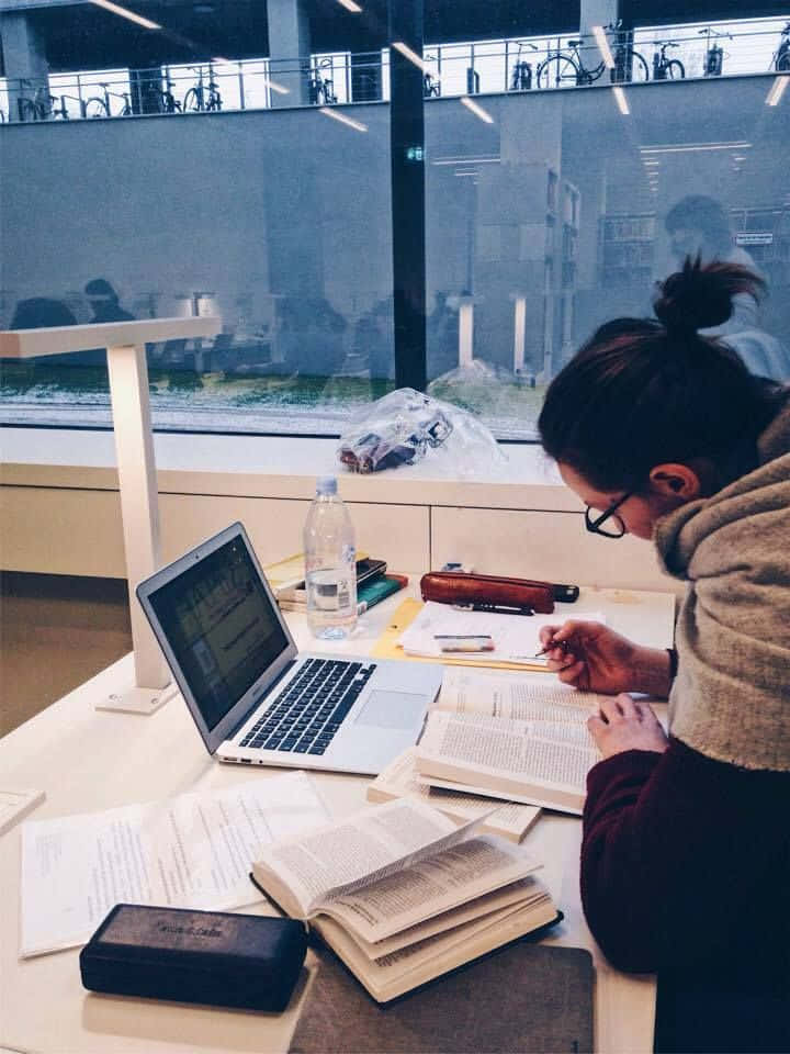 一名女子在圖書館使用筆記型電腦工作 壁紙