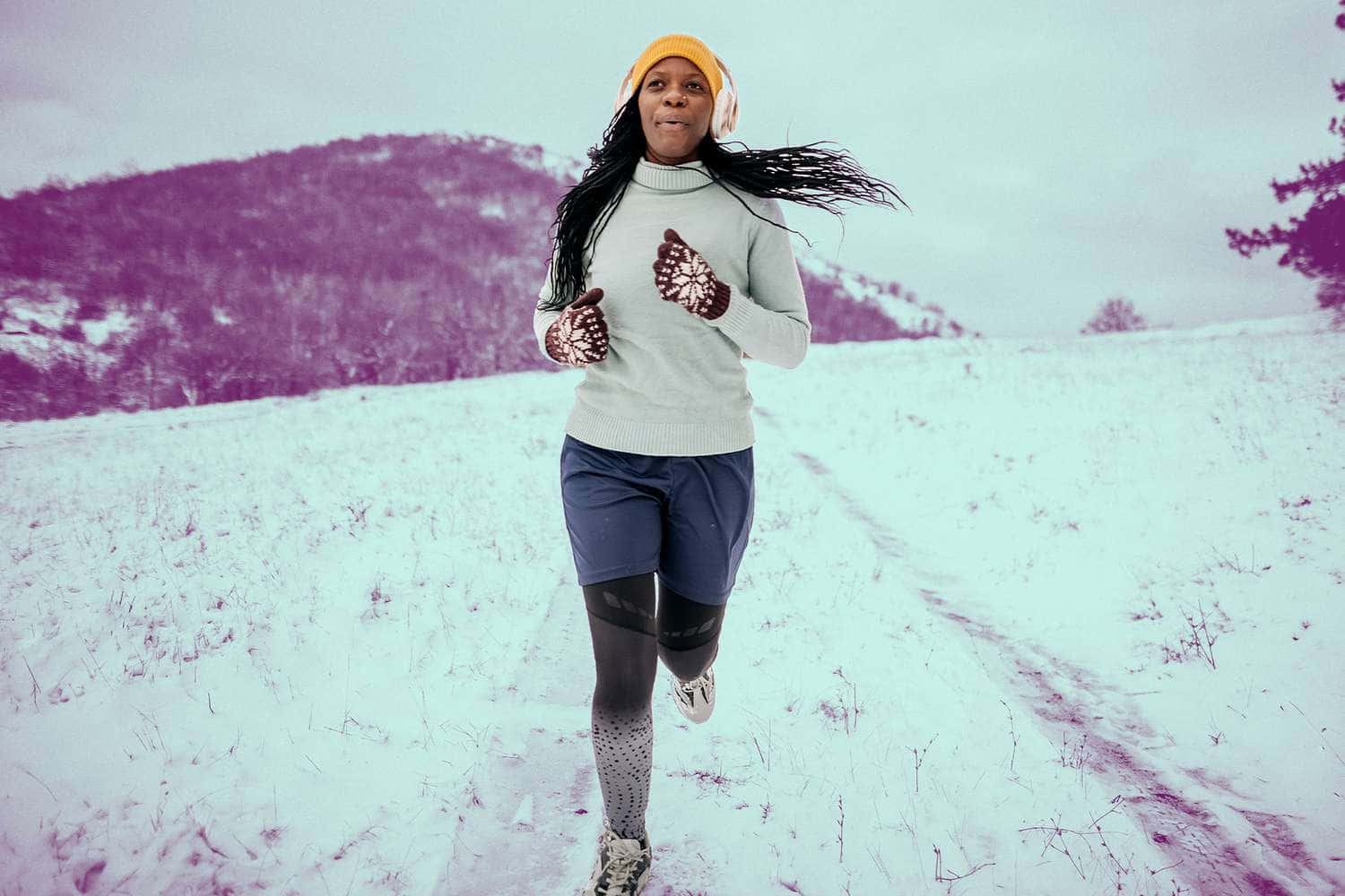 寒冷 桌布 壁紙 — 一名女子在蒼白的天空下，穿過雪地，背景是紫色的山脈。