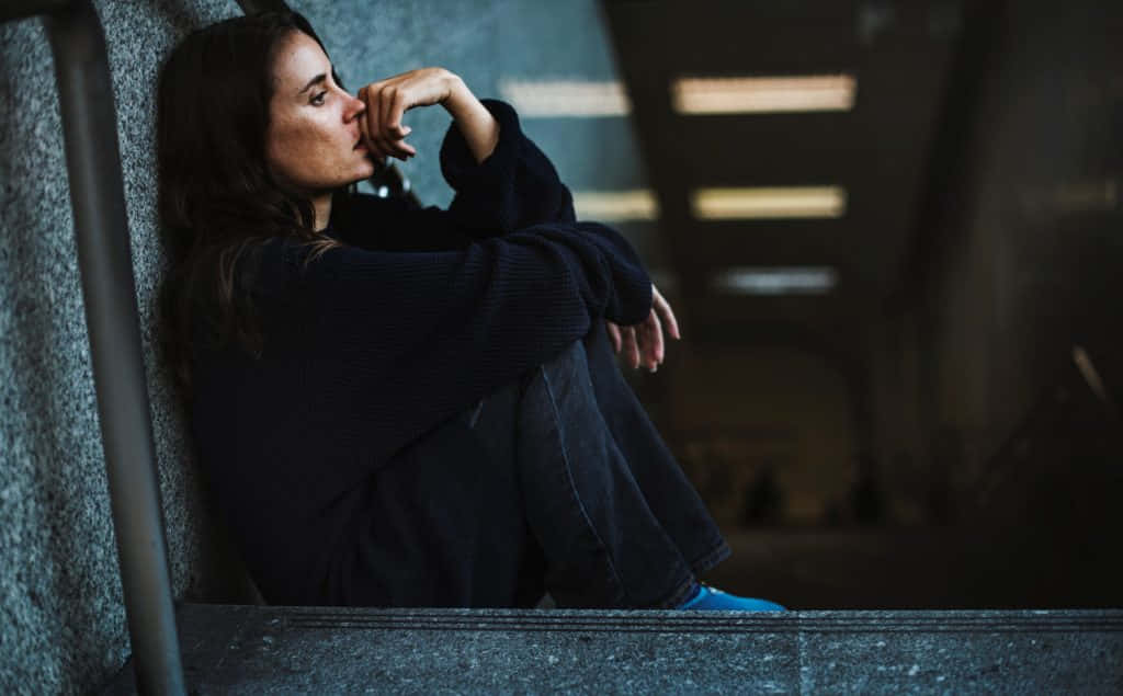 一名女子坐在空蕩走廊的樓梯上 壁紙