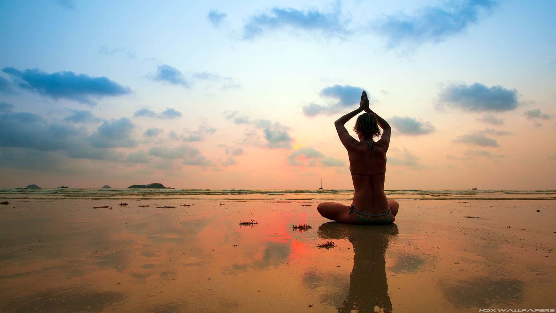 Transcendental 桌布 壁紙 — 一名女性在日落時分的濕沙灘上以蓮花坐姿冥想，她的倒影在沙中閃爍。