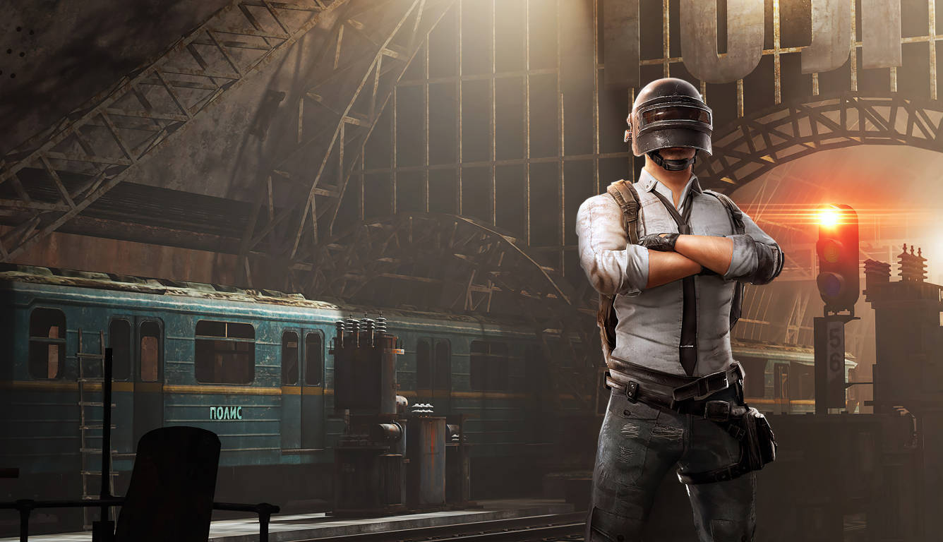 PUBG 桌布 壁紙 — 一名孤獨的士兵身穿戰術裝備，在廢棄的火車站雙臂交叉站立，金色夕陽透過破碎的拱門照射進來。