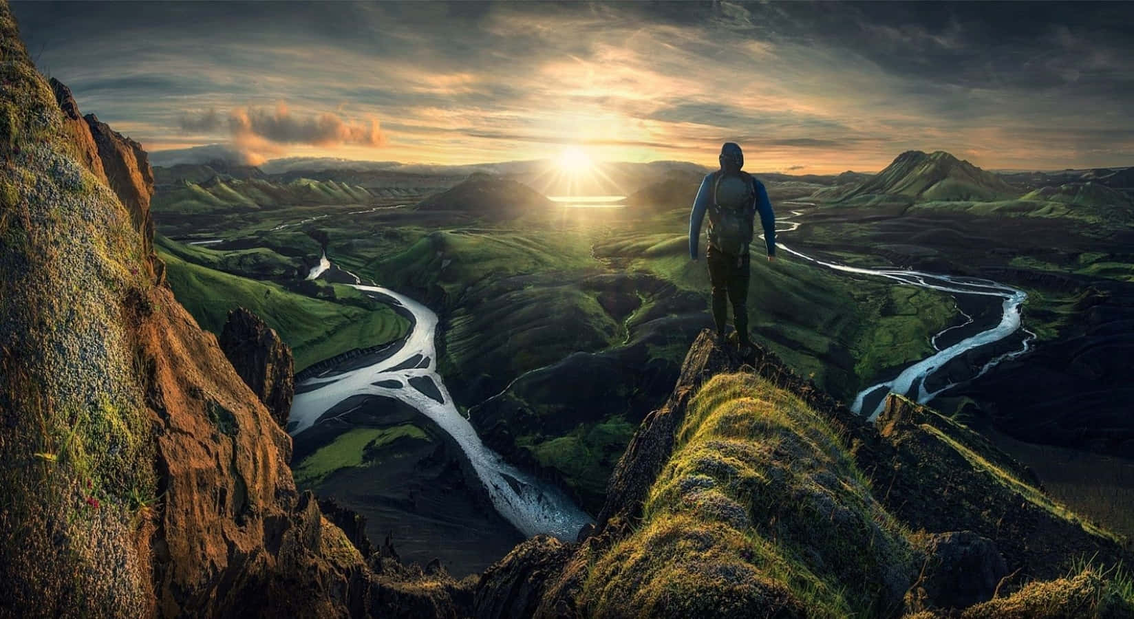3d Travel 桌布 壁紙 — 一名孤獨的遠足者站在長滿苔蘚的懸崖頂上，俯瞰著日落時分蜿蜒穿過廣闊綠色山谷的河流。