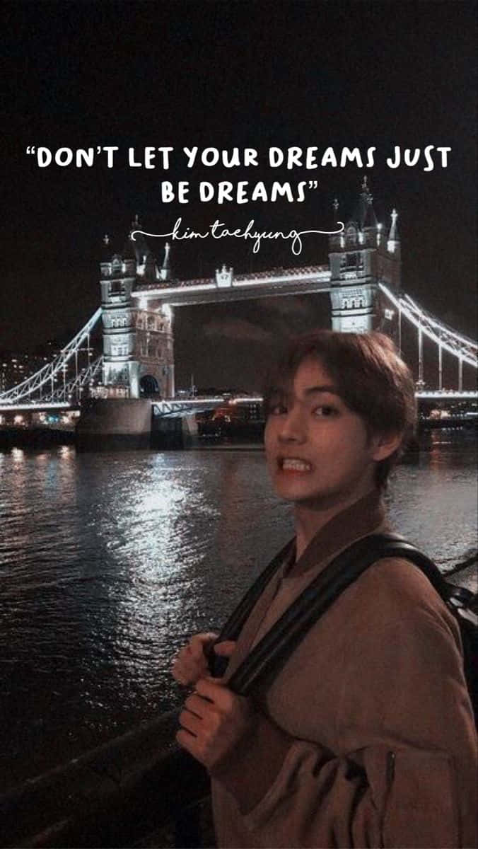 Bts Inspirational 桌布 壁紙 — 一名年輕男子在夜晚微笑地站在燈光璀璨的倫敦塔橋旁，河面倒影和勵志文字疊加。