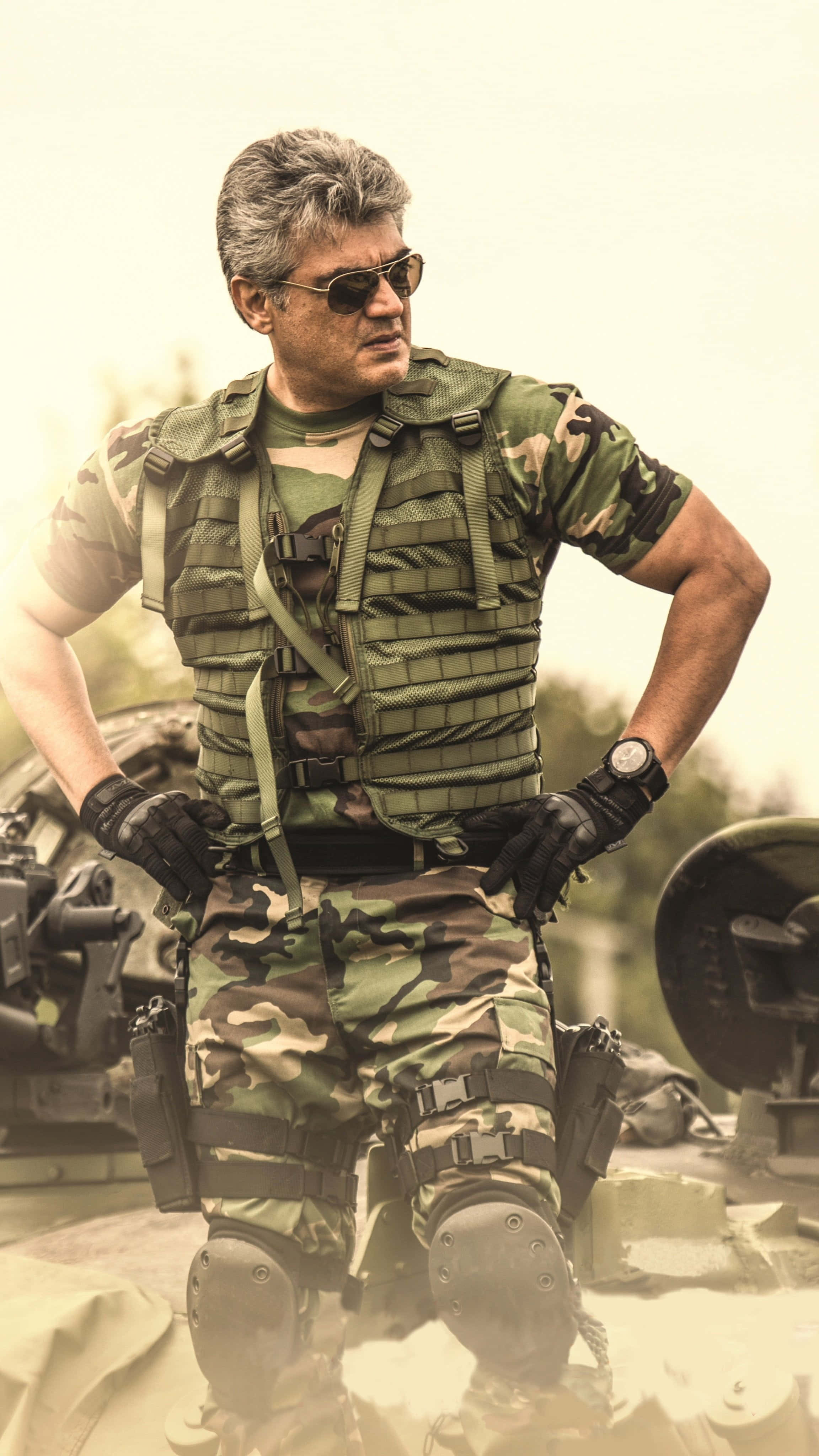 Indian Army 桌布 壁紙 — 一名強悍的士兵身穿全套迷彩裝備，雙手叉腰，自信地站在軍用坦克旁。