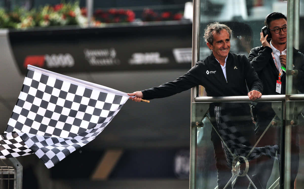 Chequered Flag 桌布 壁紙 — 一名微笑的男子在明亮的日光下，從玻璃陽台向賽車活動揮動格子旗。