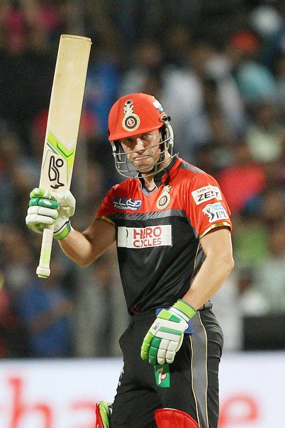 royal challengers bangalore 桌布 壁紙 — 一名戴紅色頭盔、穿黑色球衣的板球擊球手，在球場燈光下，戴著綠色手套高舉球棒。