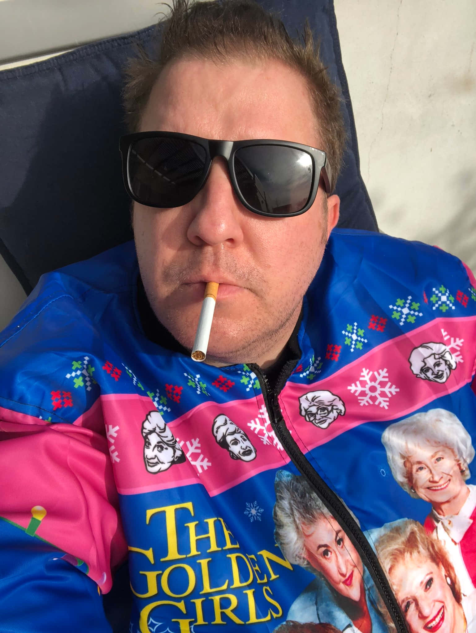 Nick Swardson 桌布 壁紙 — 一名戴著太陽眼鏡、身穿Golden Girls主題外套的男子，一邊抽煙一邊休息。