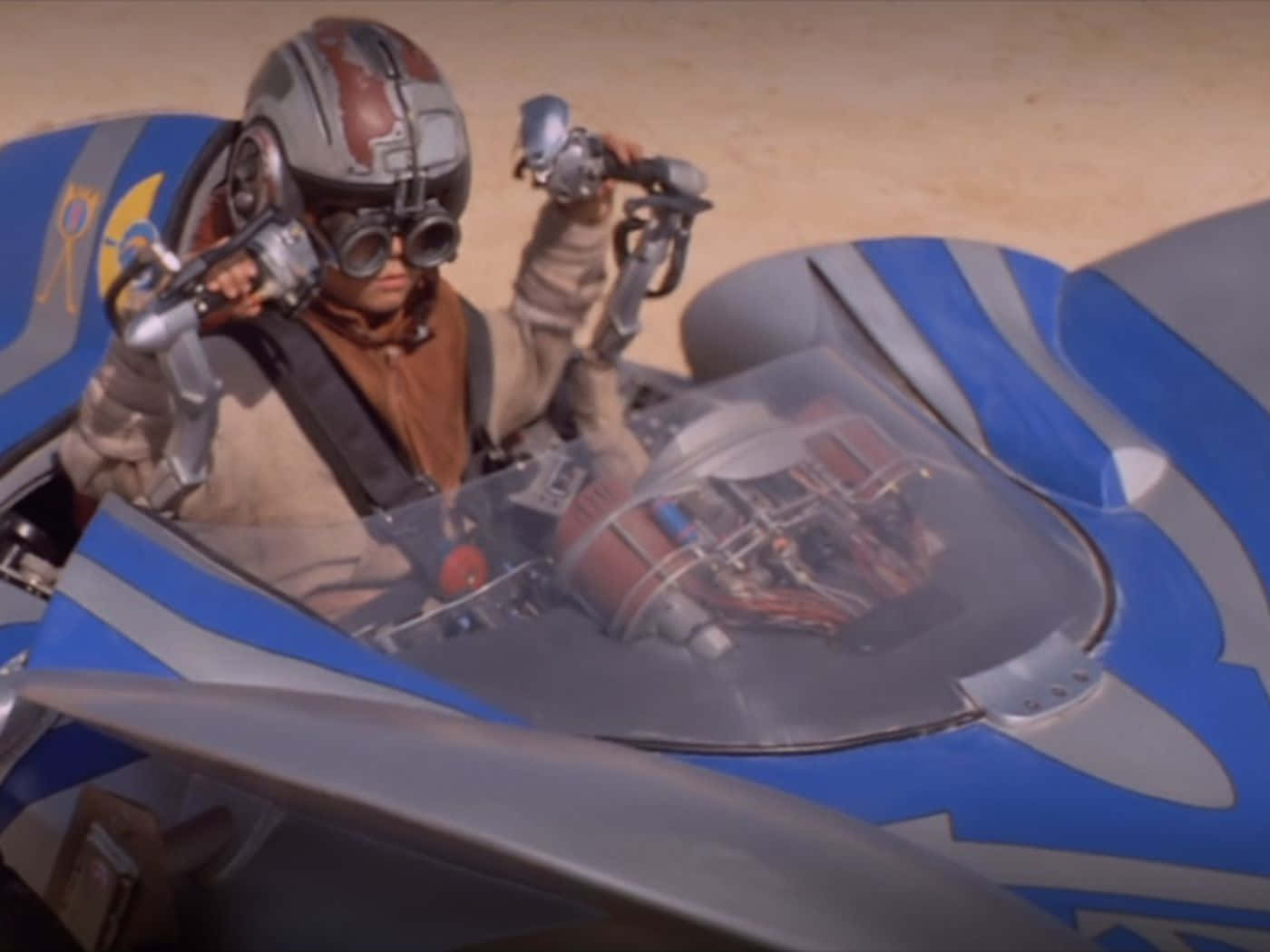 Podracing 桌布 壁紙 — 一名戴著頭盔和護目鏡的飛行員在沙質沙漠賽道上抓著一輛藍銀色飛車的控制裝置。