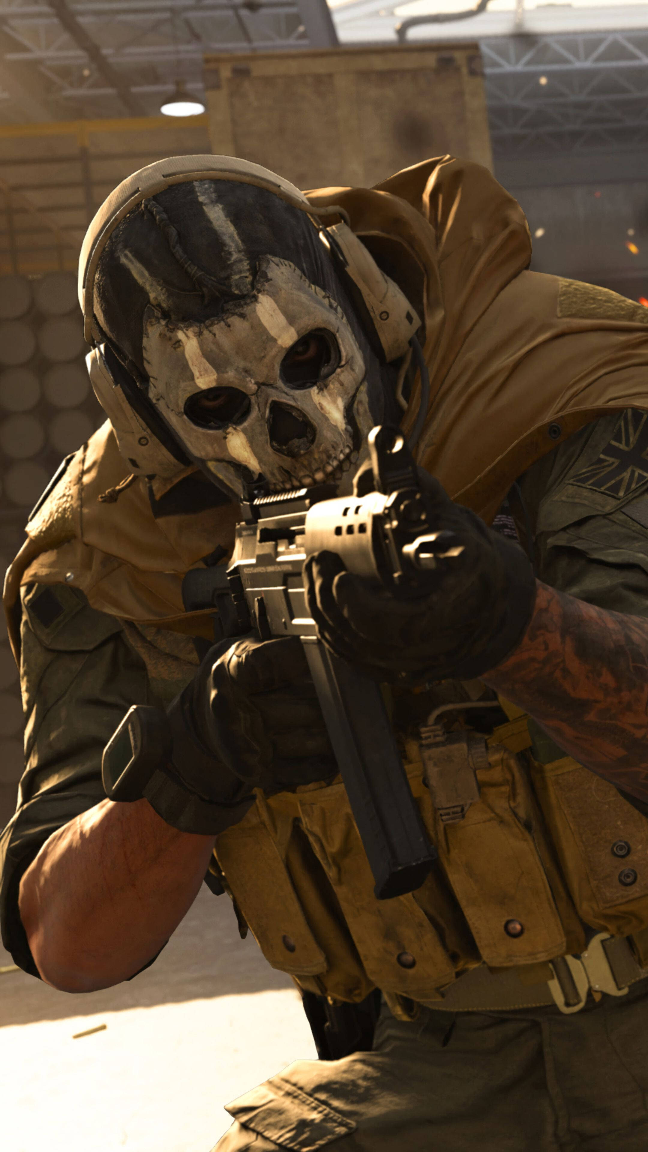 Call Of Duty Modern Warfare iPhone 桌布 壁紙 — 一名戴著骷髏面具和戰術裝備的士兵在惡劣光線下的粗糙工業倉庫中瞄準步槍。