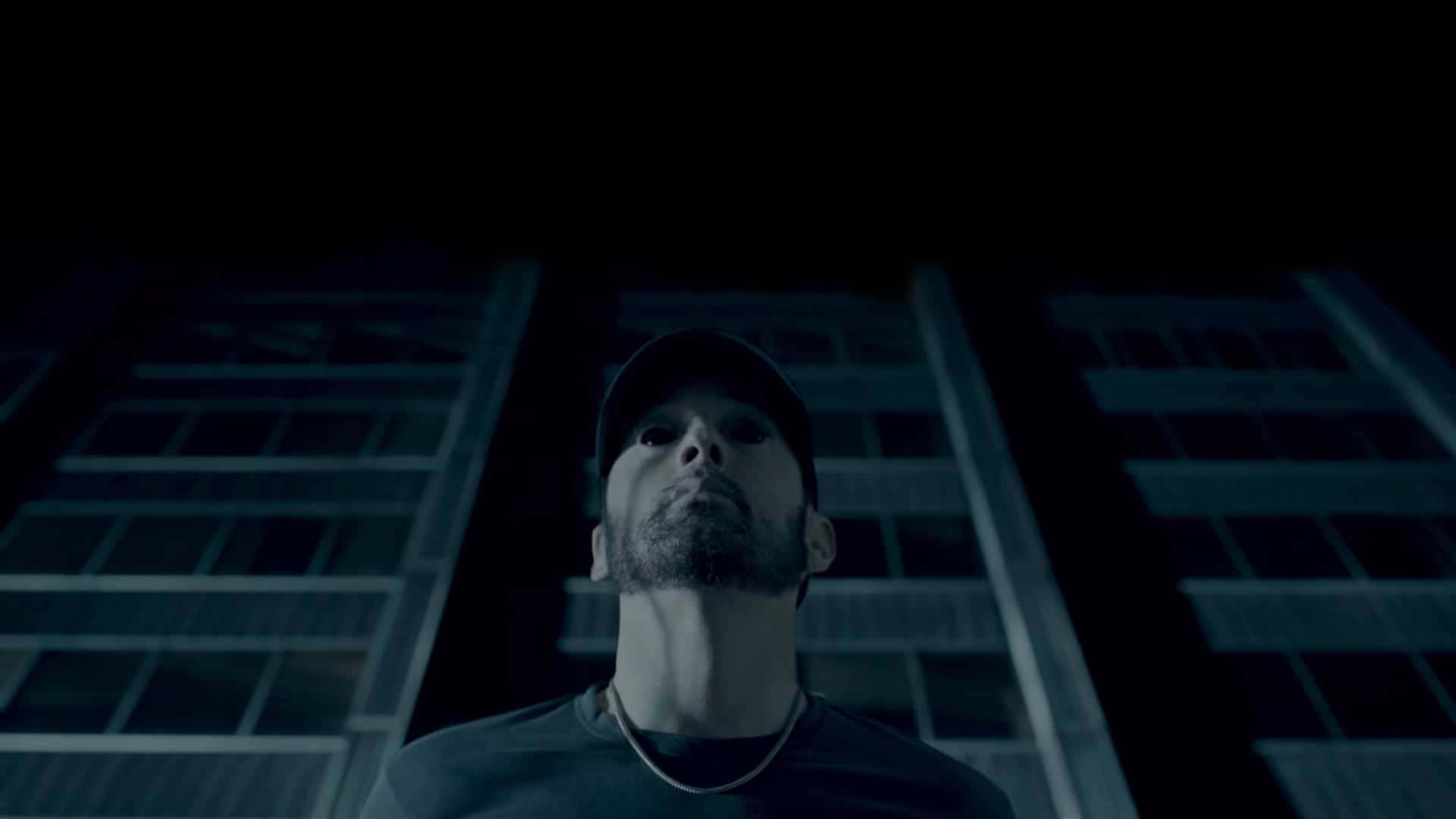 Eminem 桌布 壁紙 — 一名戴著鴨舌帽的男子在深藍色夜空下仰望高聳的城市天際線。
