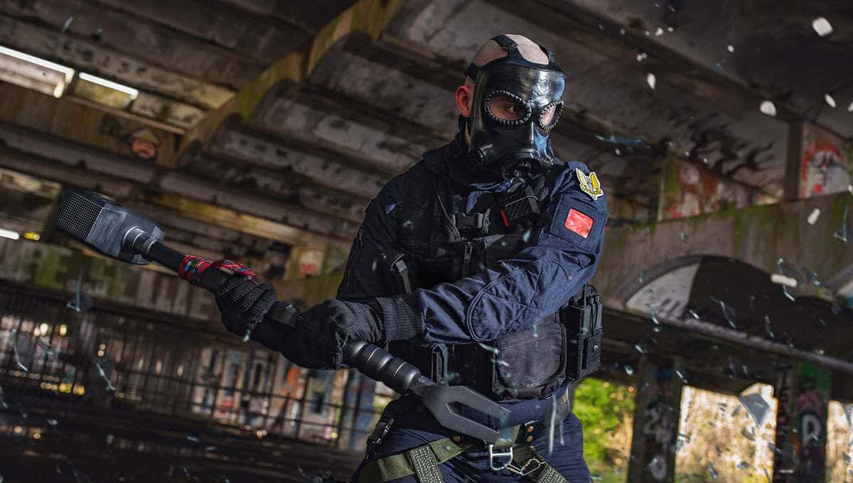 Rainbow Six Siege Sledge 桌布 壁紙 — 一名戴面具的戰術特工身穿黑色裝備，在破舊橋樑下的粗糙城市環境中砸碎玻璃。