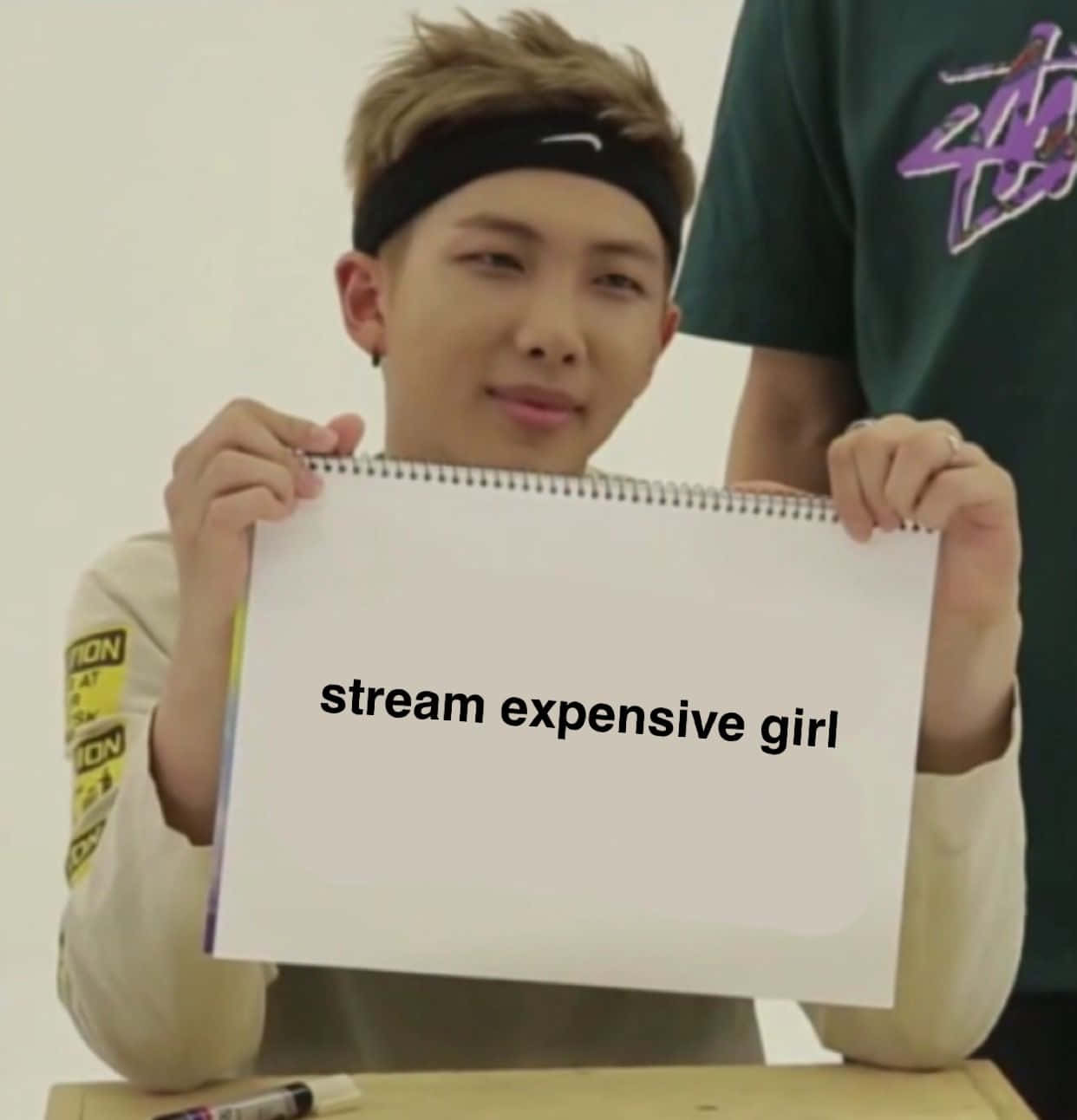 Bts Meme 桌布 壁紙 — 一名戴頭帶的年輕男子坐在桌旁，舉起一個白色記事本，上面顯示文字 stream expensive girl。