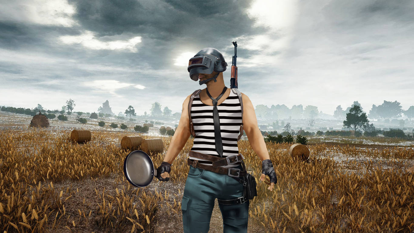 PUBG 桌布 壁紙 — 一名戴頭盔、穿條紋襯衫的遊戲玩家在暴風雨天空下的小麥田裡拿著煎鍋和步槍。