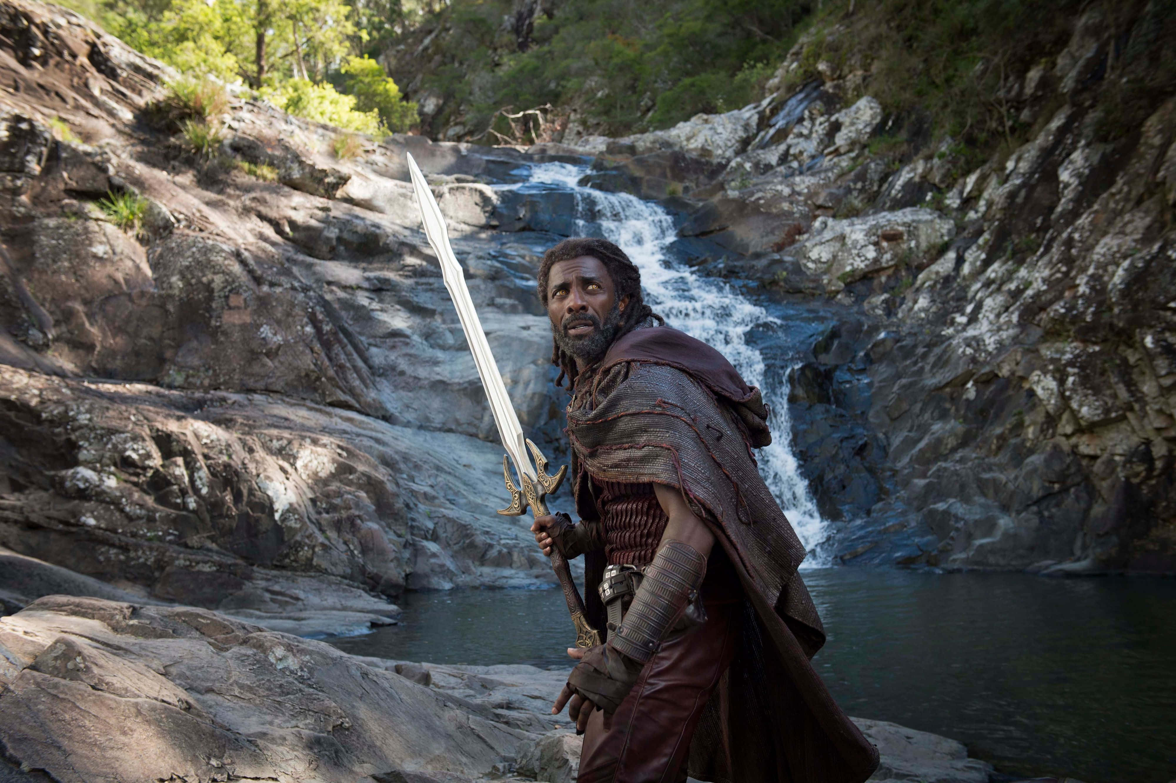 Heimdall 桌布 壁紙 — 一名手持長劍的戰士站在崎嶇森林峽谷中的瀑布前。