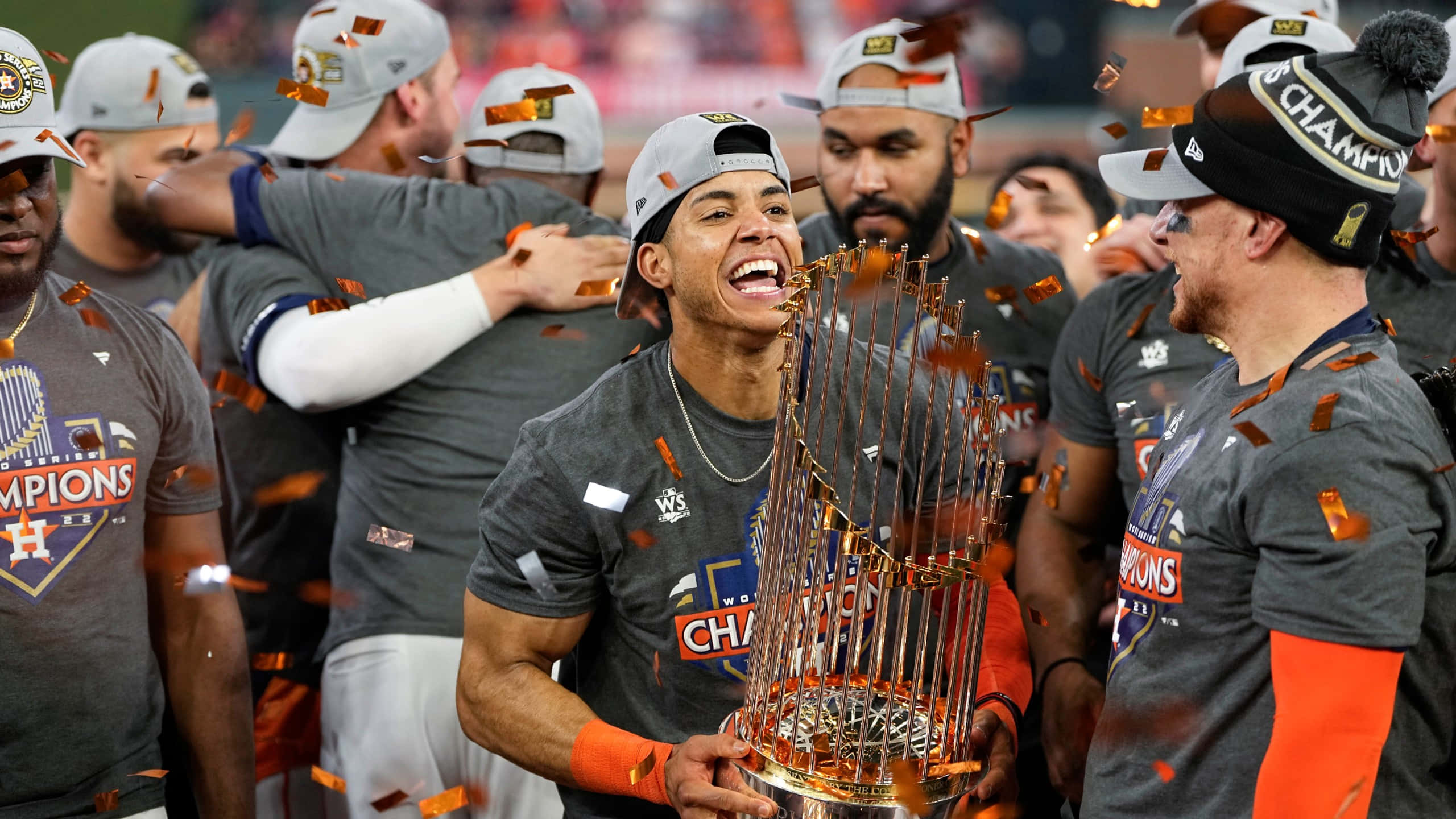 Astros 桌布 壁紙 — 一名棒球運動員滿面笑容地拿著閃閃發光的獎盃，隊友們在周圍飄落的五彩紙屑中慶祝。
