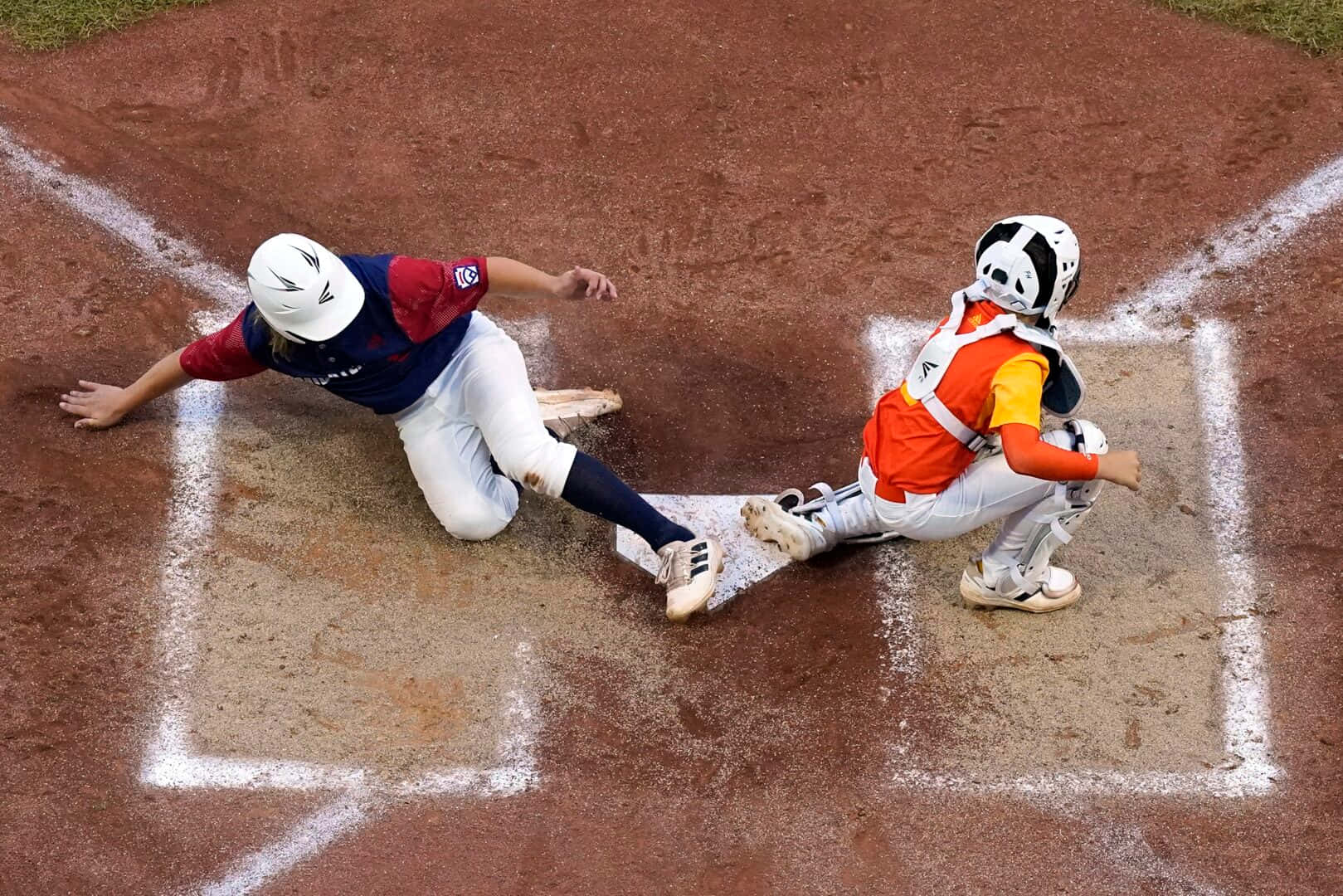 Little League Baseball 桌布 壁紙 — 一名棒球選手頭部滑入本壘，而身穿橙色裝備的捕手飛撲試圖觸殺她。
