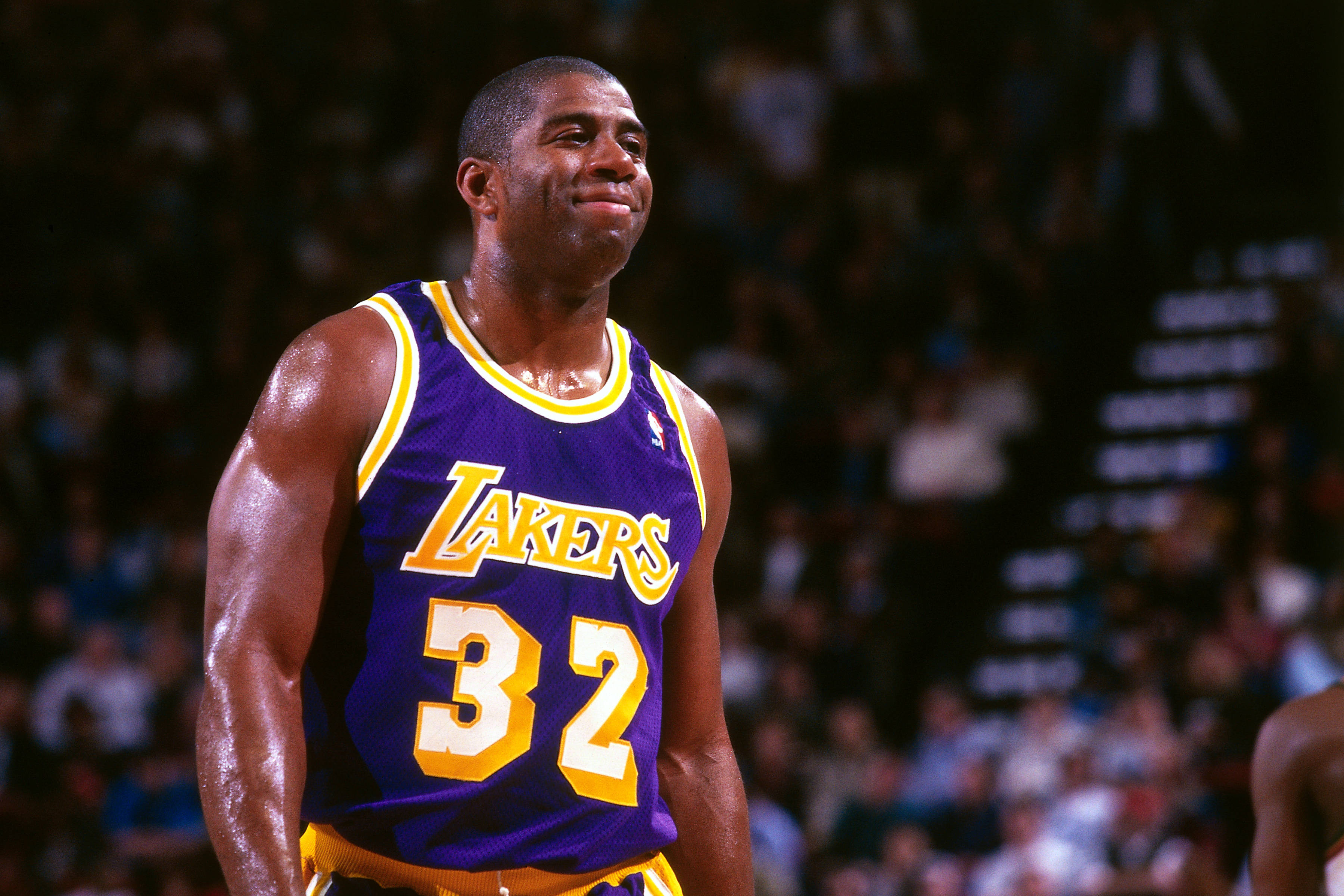 NBA 桌布 壁紙 — 一名汗流浹背的籃球運動員身穿紫色湖人隊32號球衣，在明亮的球場燈光下自信地微笑。