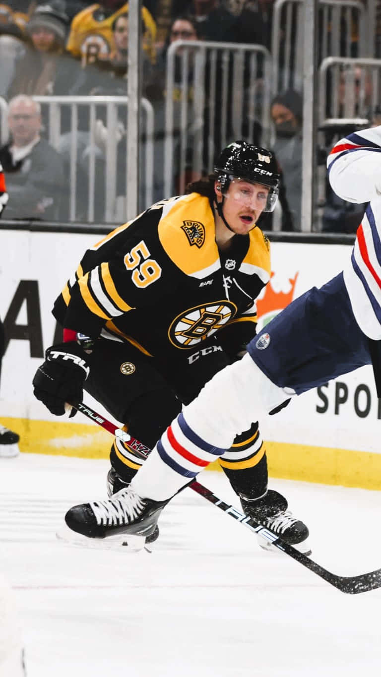 Tyler Bertuzzi 桌布 壁紙 — 一名波士頓棕熊冰球球員身穿黑色和金色裝備，在場館燈光下於冰上與對手爭奪冰球。