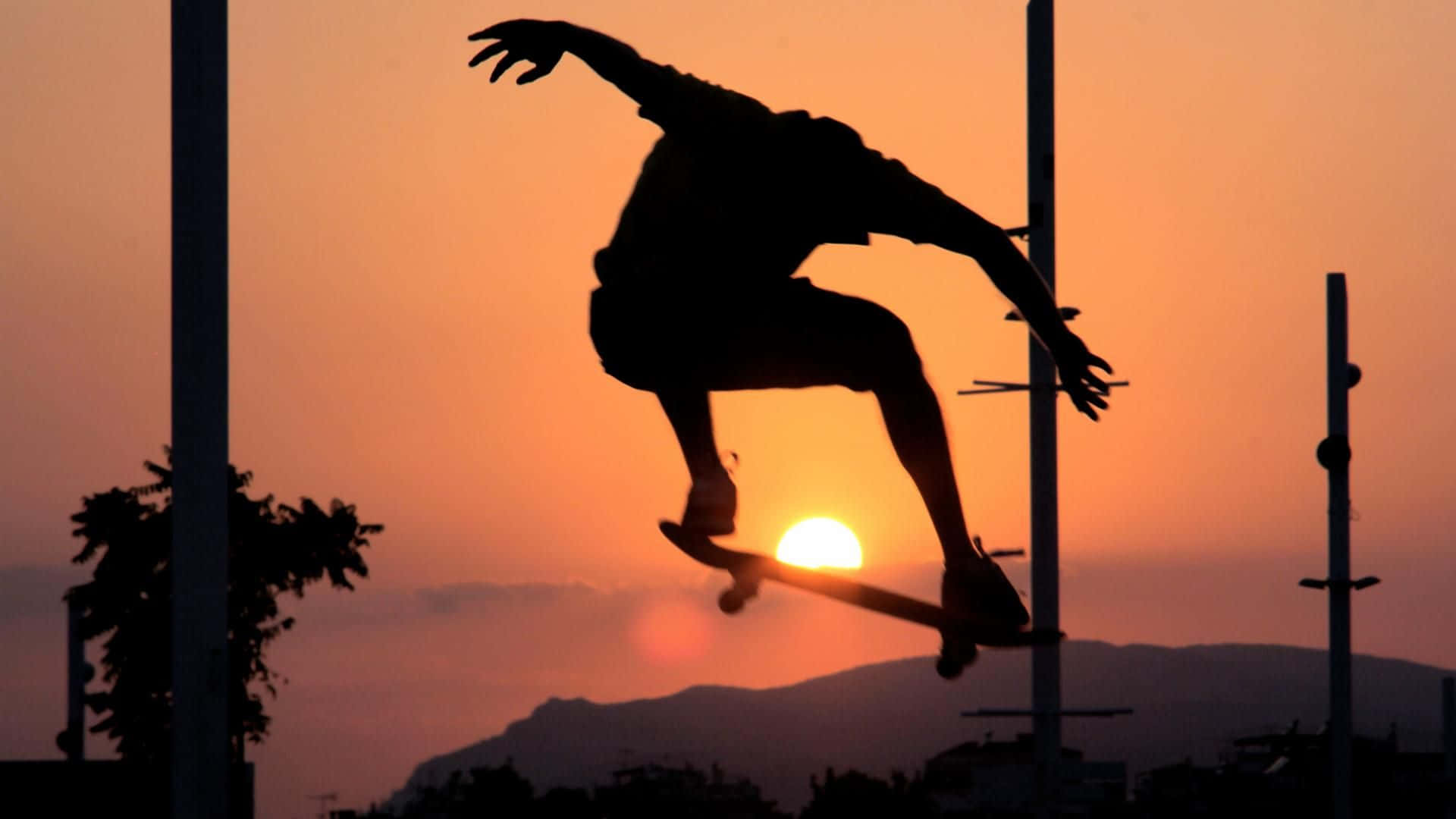 skateboarding 桌布 壁紙 — 一名滑板選手的剪影在熾熱的夕陽中騰空而起，太陽在他們身後發光。