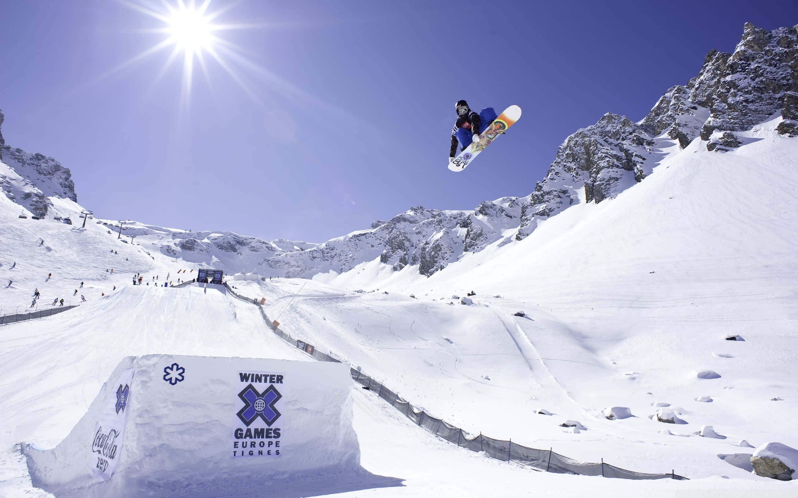 Winter Games 桌布 壁紙 — 一名滑雪板運動員在 Winter X Games Europe 的雪坡上，於熾熱的陽光下在空中翱翔。
