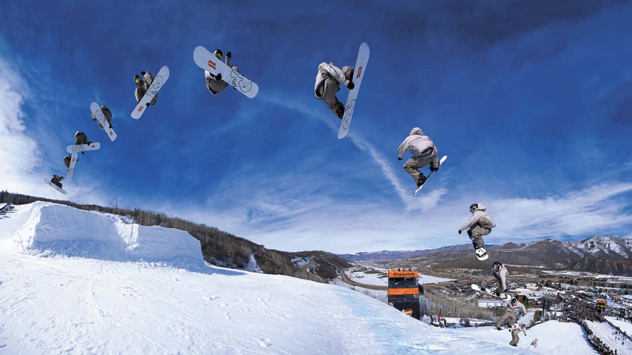 Winter Sports 桌布 壁紙 — 一名滑雪板運動員在白雪覆蓋的山坡上空，以多個連續姿勢捕捉於空中，背景是鮮豔的藍天。
