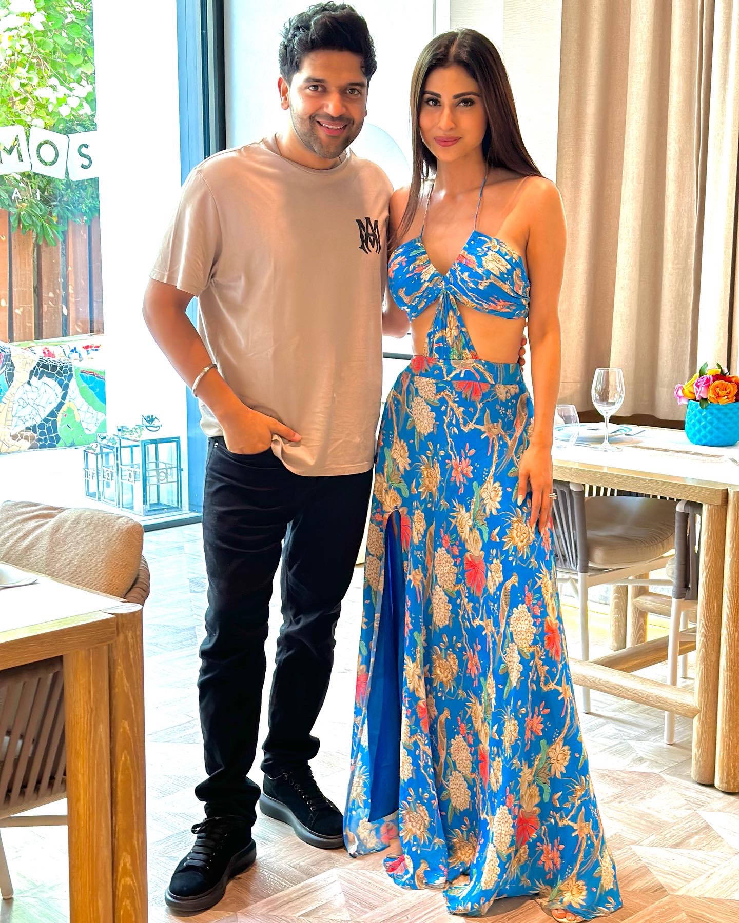 Guru Randhawa 桌布 壁紙 — 一名男子和一名女子在室內靠近窗戶的地方擺姿勢，窗外有明亮的自然光，周圍有現代家具。