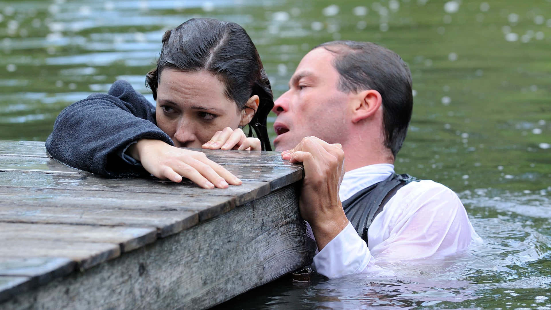 Rebecca Hall 桌布 壁紙 — 一名男子和女子在渾濁的水中掙扎，絕望地抓緊一個風化的木碼頭。