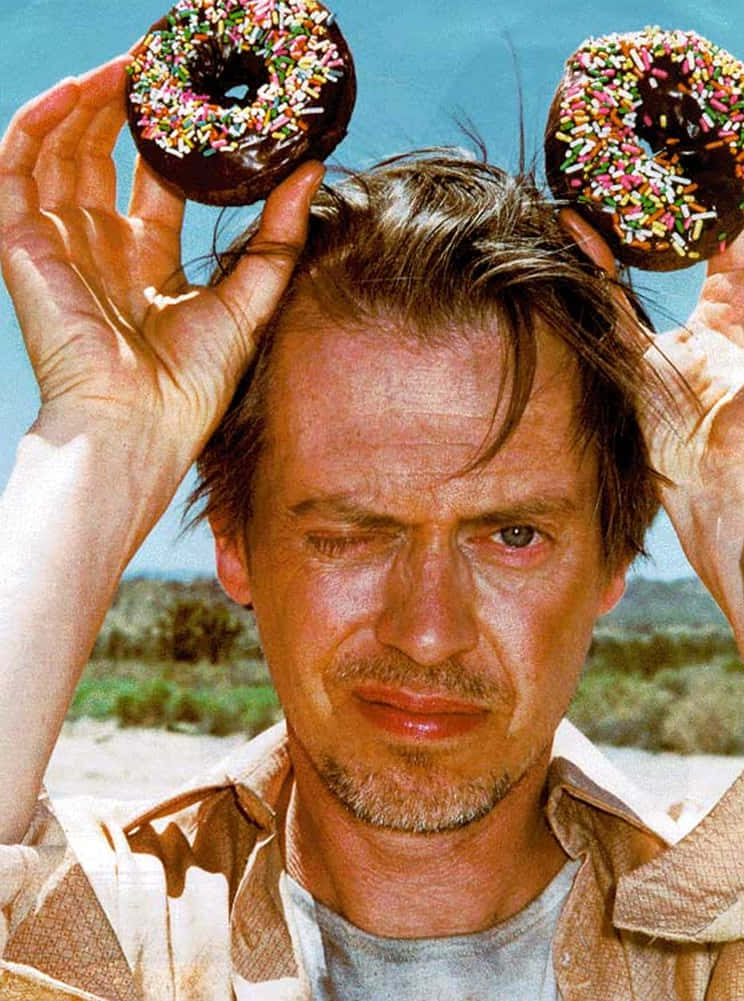 steve buscemi 桌布 壁紙 — 一名男子在明亮的藍天和沙漠背景下，將兩個朱古力彩針冬甩放在頭上。