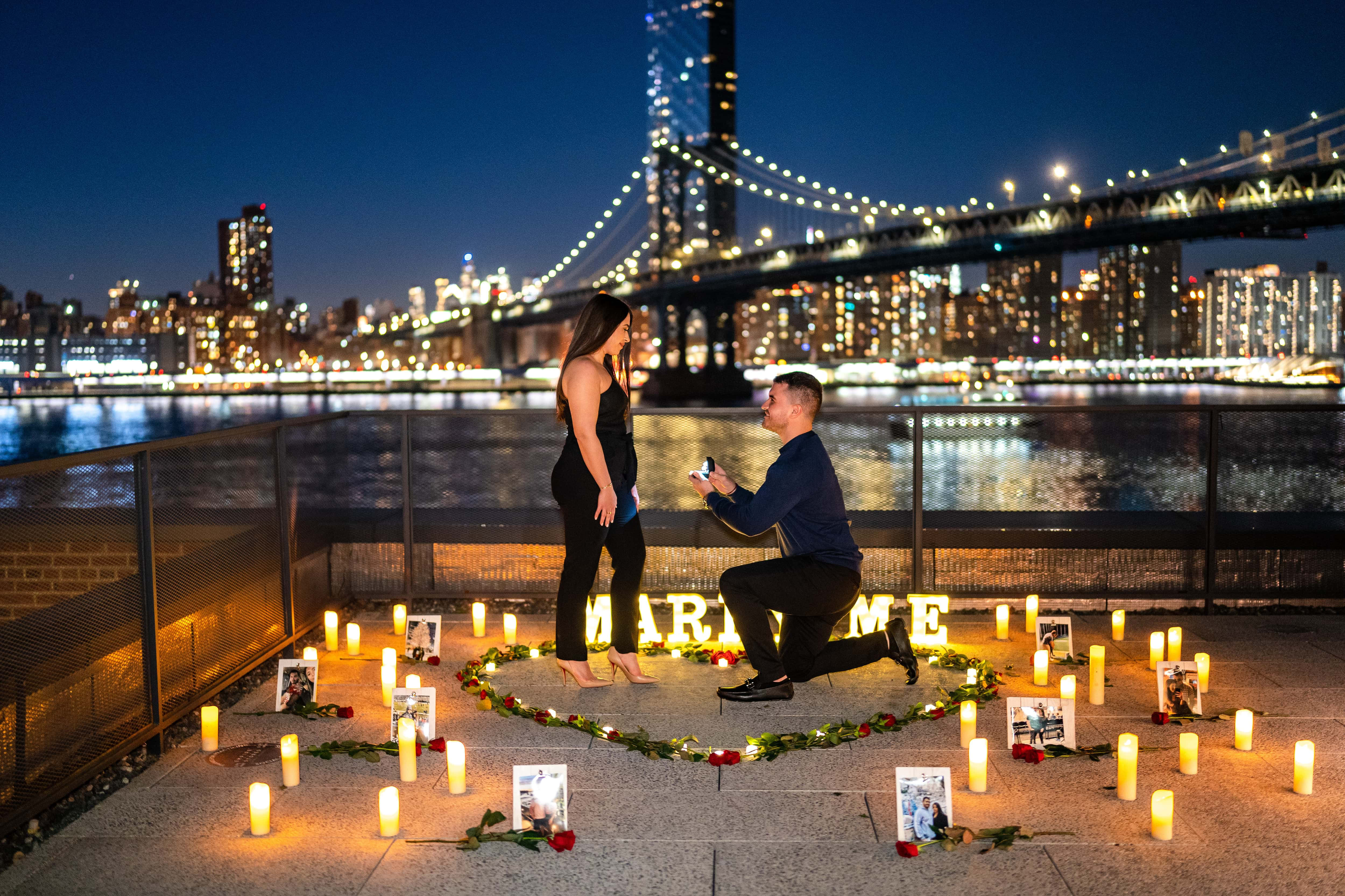 Proposal 桌布 壁紙 — 一名男子在晚上跪在屋頂上，用蠟燭和照片在燈光橋下形成心形向一名女子求婚。