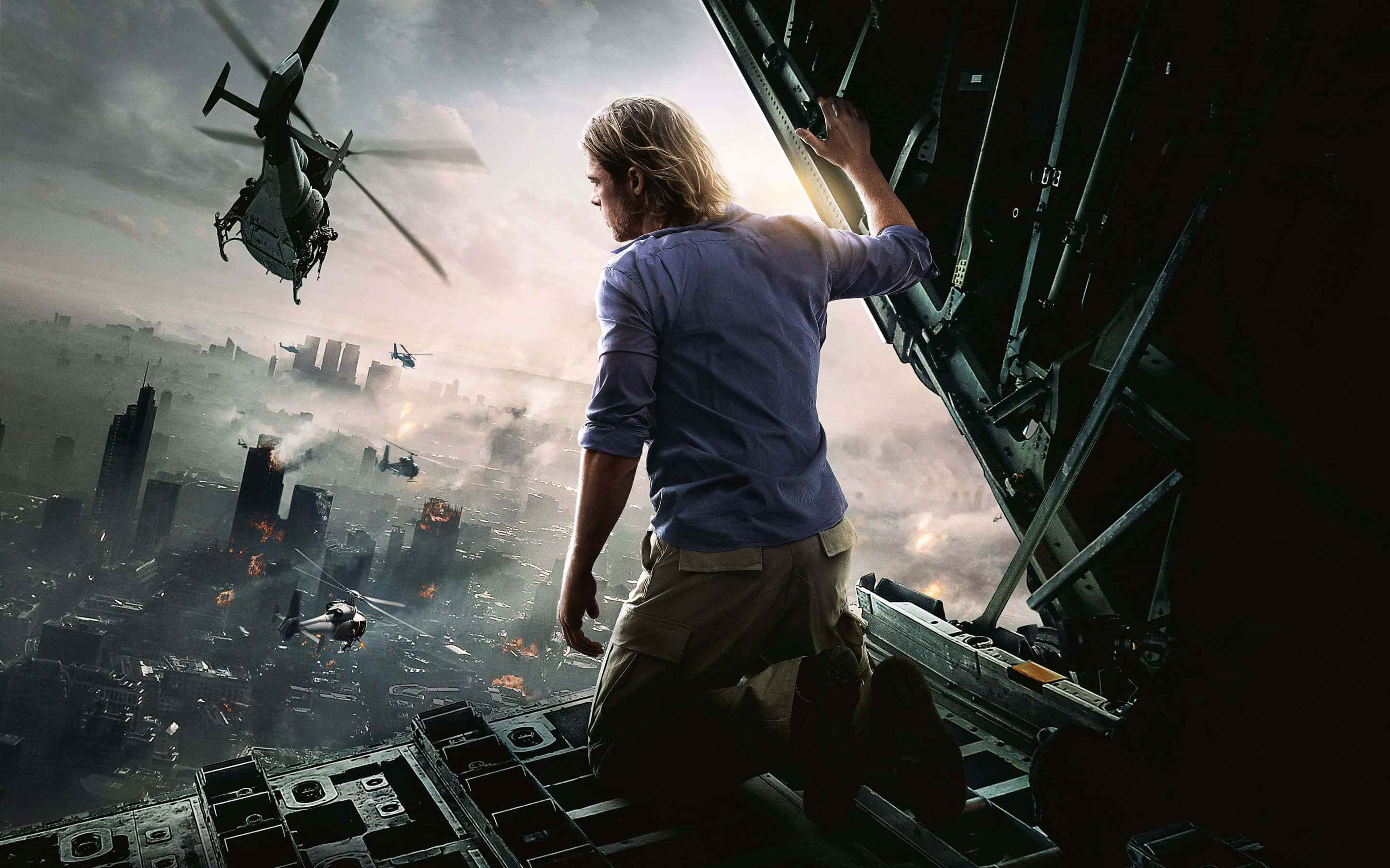 Action Movie 桌布 壁紙 — 一名男子跪在戰機邊緣，俯瞰著燃燒的城市，直升機在煙霧彌漫的天空中飛行。