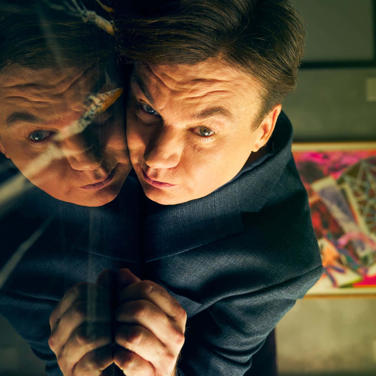 Mike Myers 桌布 壁紙 — 一名男子透過污跡斑斑的玻璃表面專注地凝視，旁邊是他扭曲的倒影。