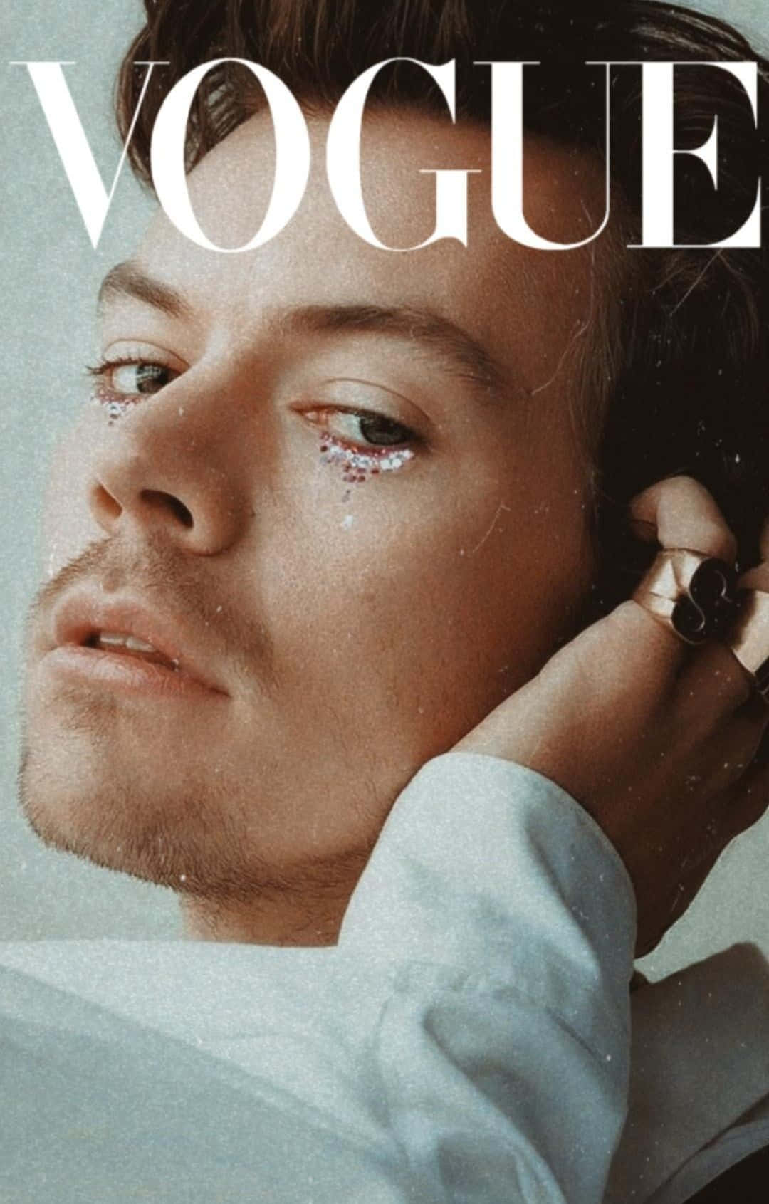Magazine 桌布 壁紙 — 一名男子閉眼特寫肖像，眼瞼上帶有閃粉，手靠近臉部，背景是Vogue雜誌封面。