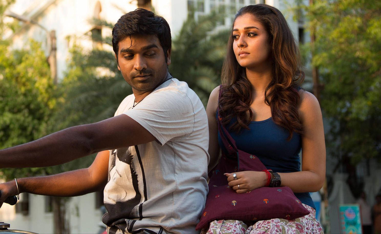 vijay HD 桌布 壁紙 — 一名男子騎著單車，後座坐著一名女子，兩人一同望向陽光普照、綠樹成蔭的都市街道前方。