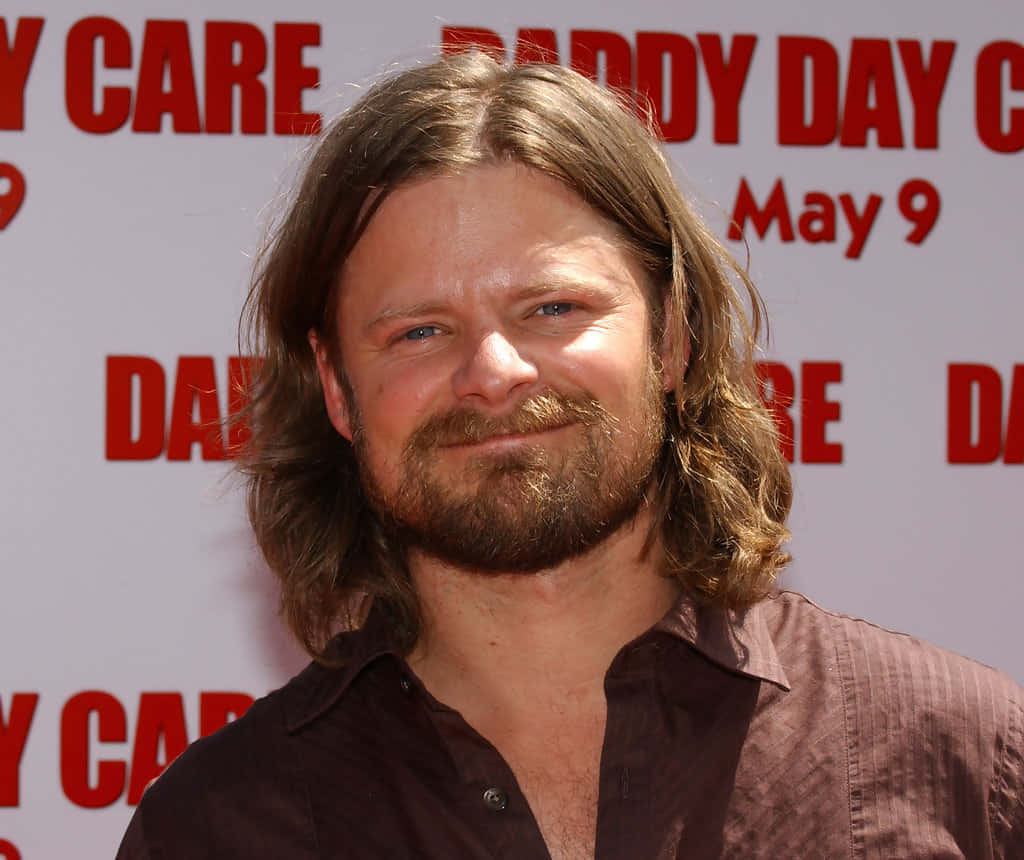 Steve Zahn 桌布 壁紙 — 一名留著棕色長髮和鬍鬚的男子，在紅白相間的電影首映背景前對著鏡頭微笑。