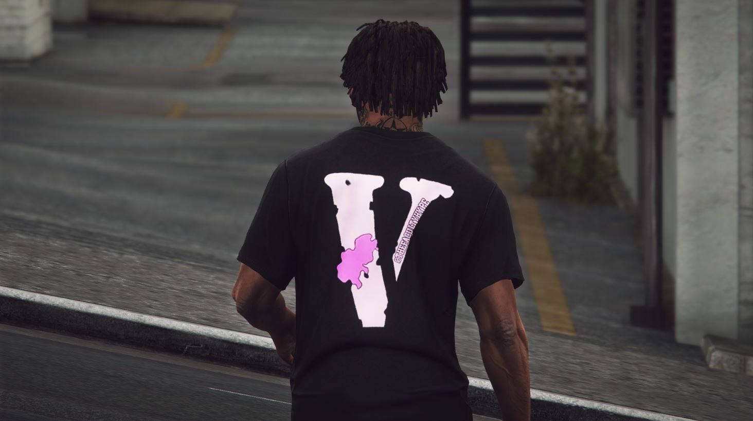 Vlone 桌布 壁紙 — 一名留著辮子頭的男人，穿著一件帶有大型白色V標誌和粉紅色圖案的黑色T恤，沿著濕漉漉的城市街道走開。