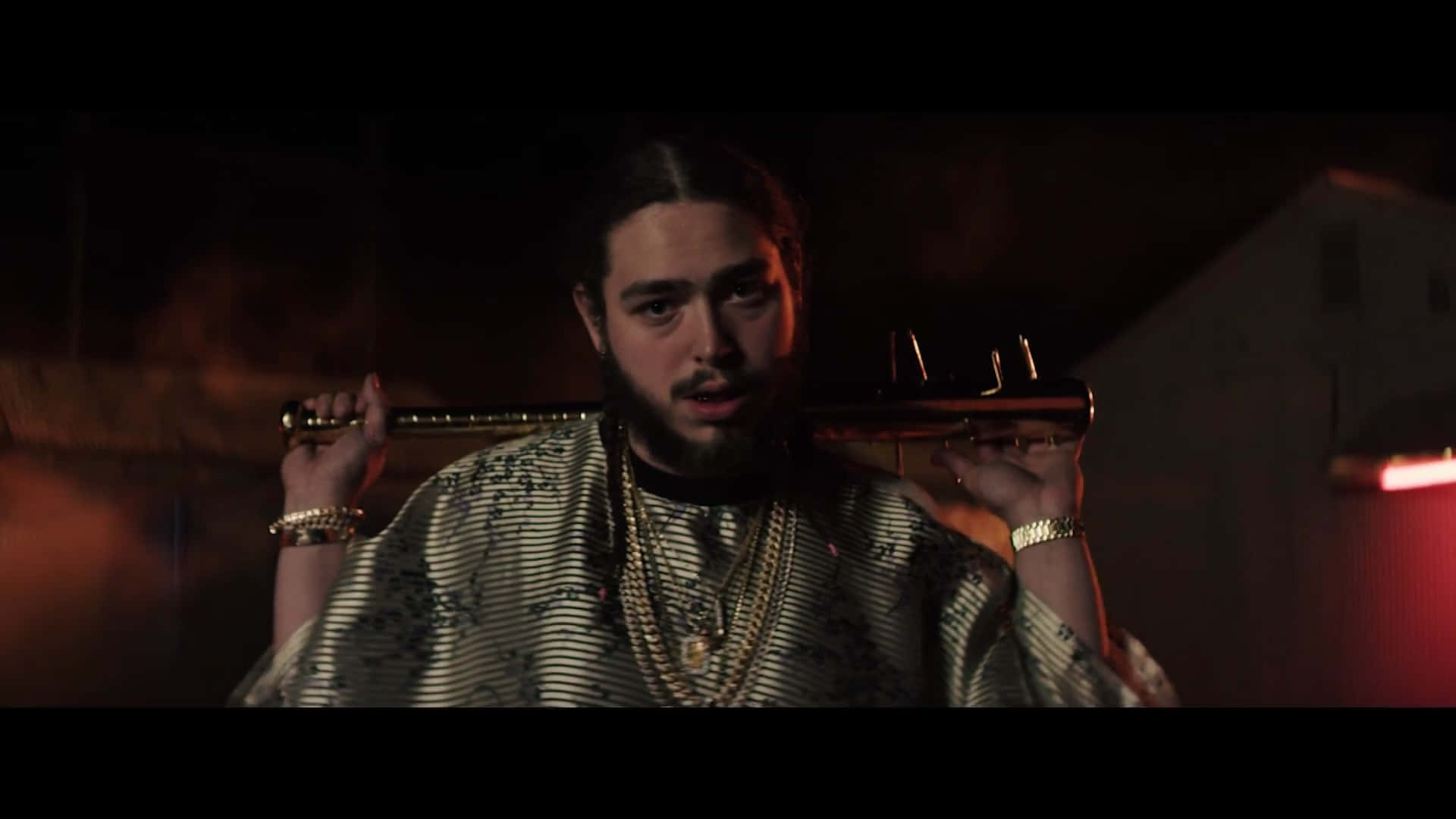 Post Malone 桌布 壁紙 — 一名留鬍子、戴金鏈的男子在夜晚昏暗的城市小巷中，將棒球棍扛在肩上。