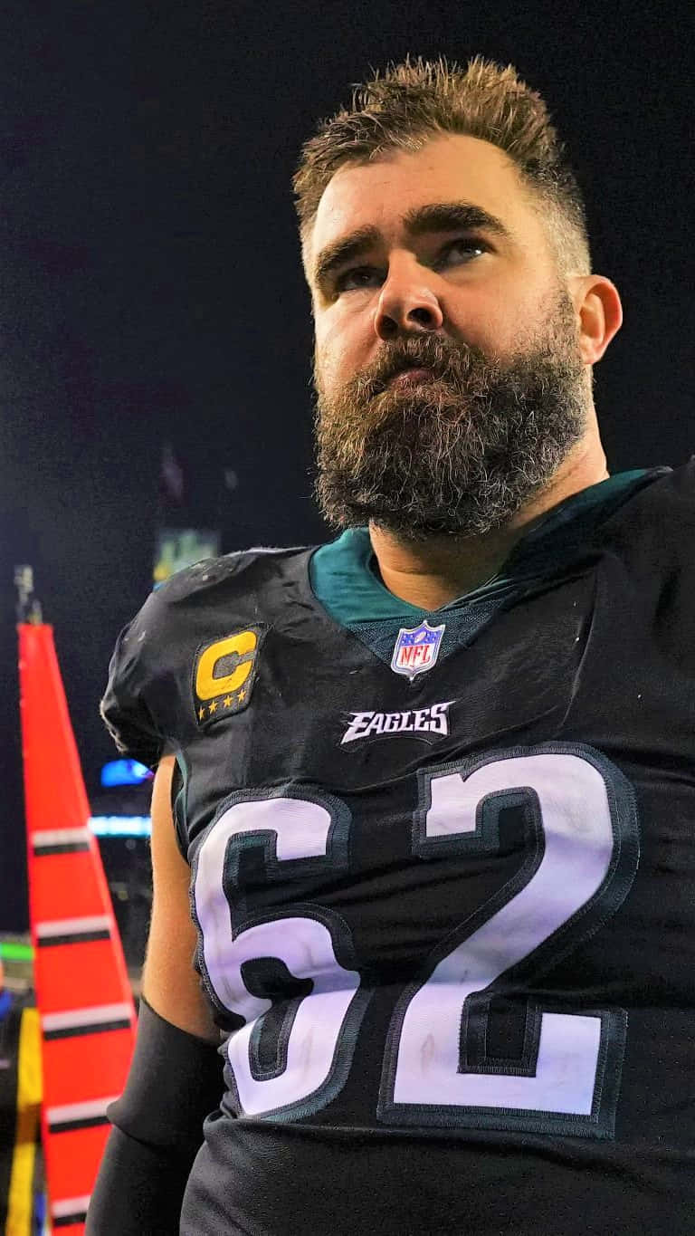 Jason Kelce 桌布 壁紙 — 一名留鬍鬚的NFL美式足球員，身穿黑色Eagles球衣（號碼62，附隊長臂章），在球場燈光下的特寫。