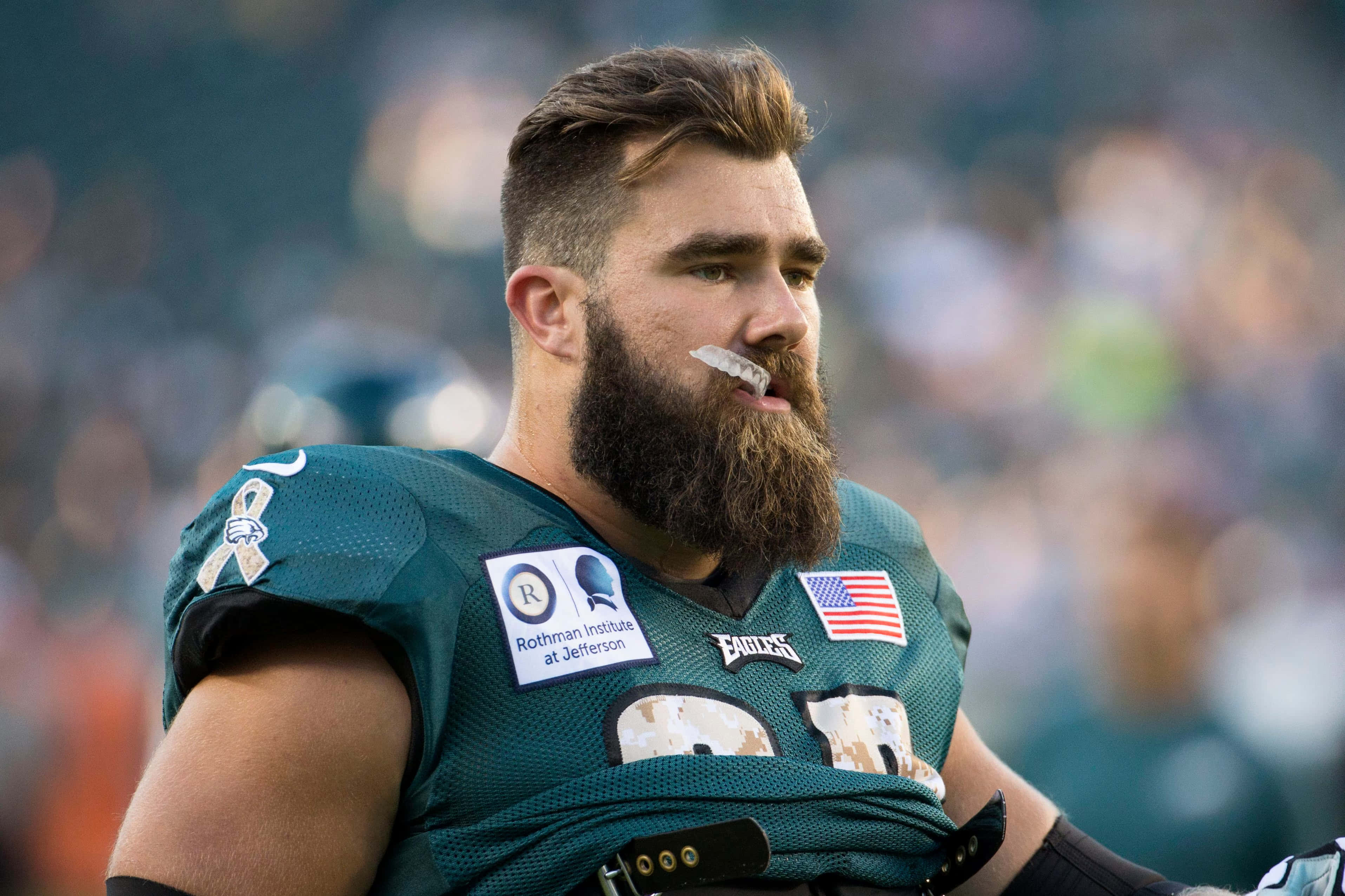 Jason Kelce 桌布 壁紙 — 一名留鬍鬚的足球員身穿綠色Eagles球衣，戴著護齒和補丁，比賽中的特寫。